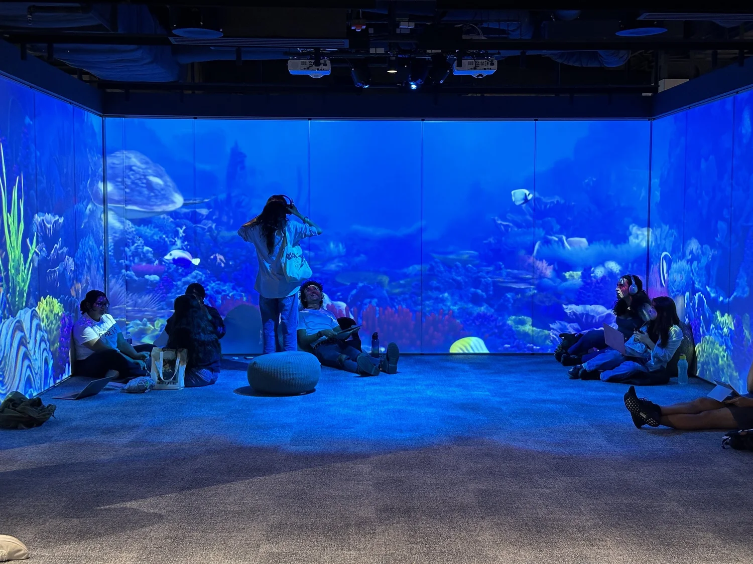 Visitors surrounded by underwater imagery across three projection walls
