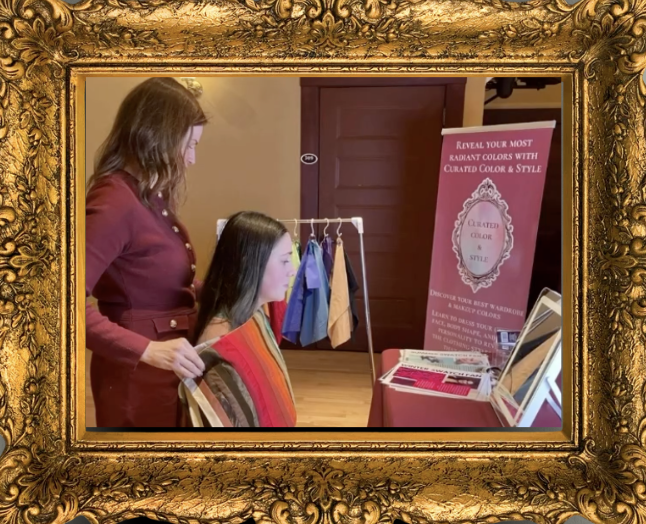 A woman helping a young woman explore fabric and color options at a color consultation exhibit, with fabric swatches on a clothing rack and informational signs in the background.