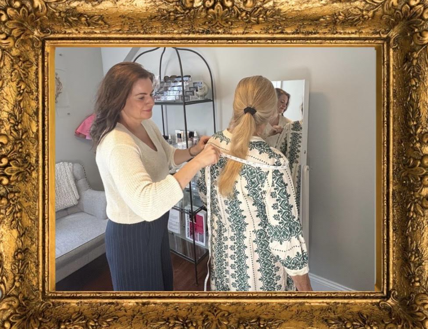 A hairstylist measuring a woman's hair in a mirror in a salon.
