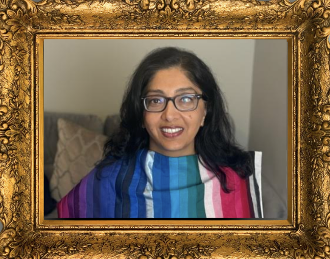 A woman with glasses, long black hair, and a colorful striped shawl, smiling, appears in a decorative gold frame.