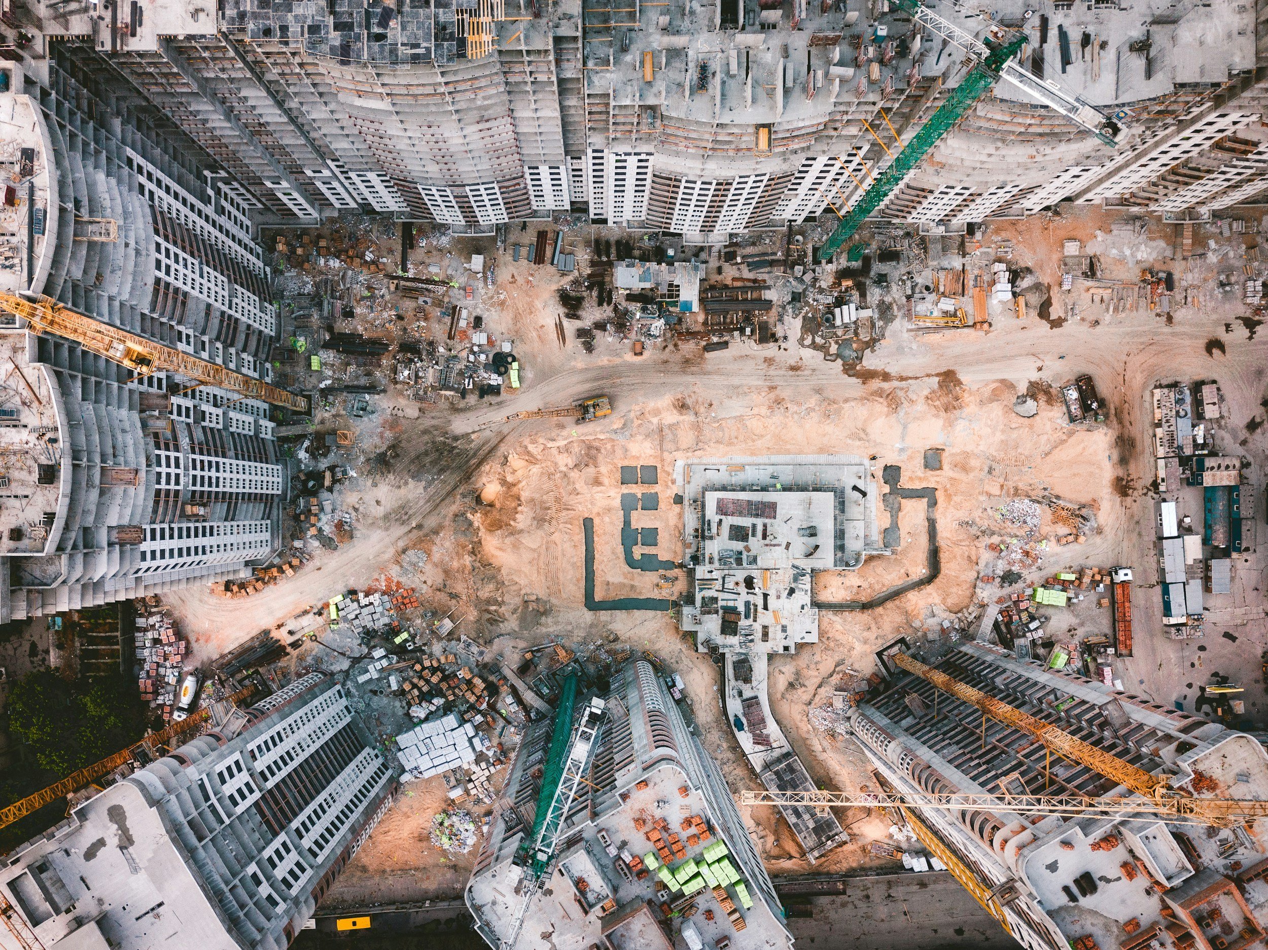 Aerial view of a construction site with high-rise buildings under construction, cranes, and building materials.