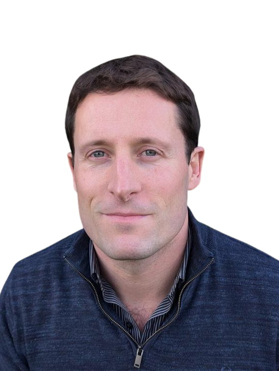 A man with short brown hair and blue eyes, wearing a navy zip-up sweater over a striped shirt, looks at the camera with a neutral expression.