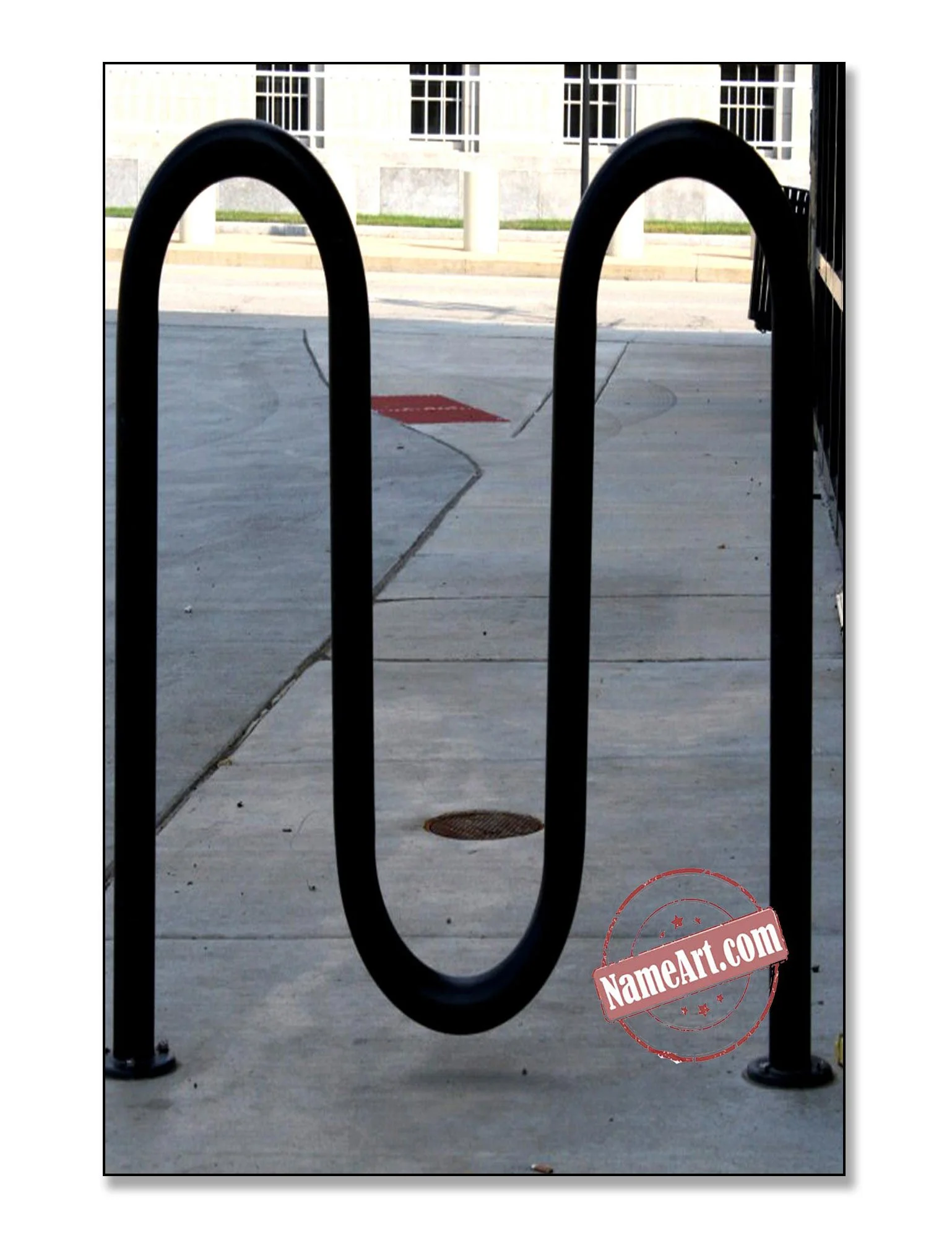 A black metal bike rack shaped like a large zero on a concrete sidewalk