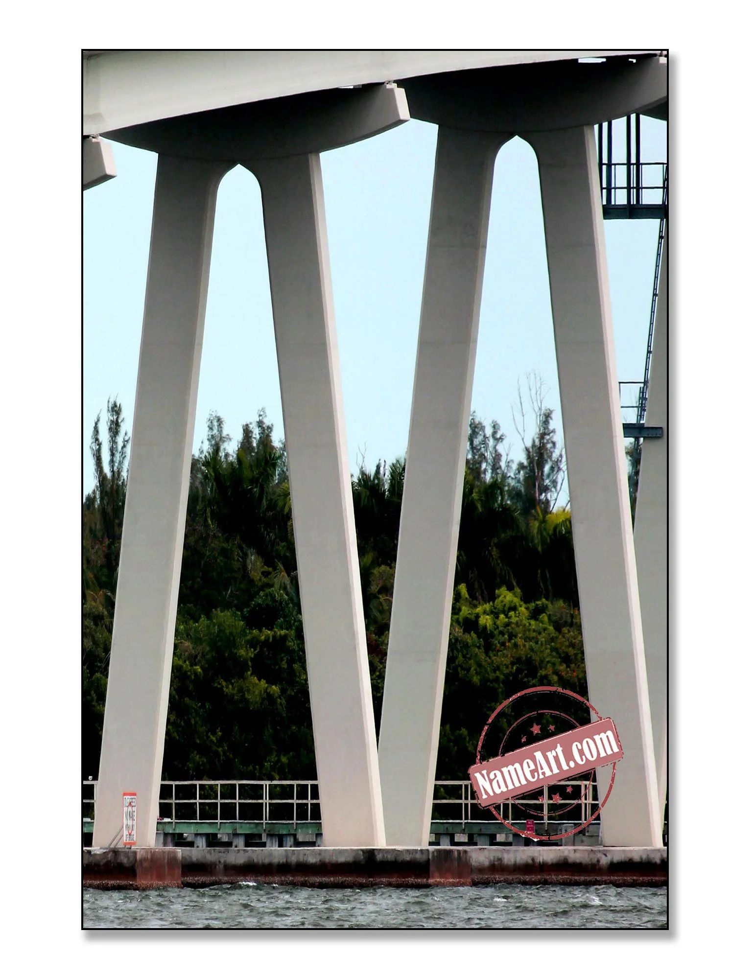 Close-up view of a bridge's support beams with water and trees in the background.