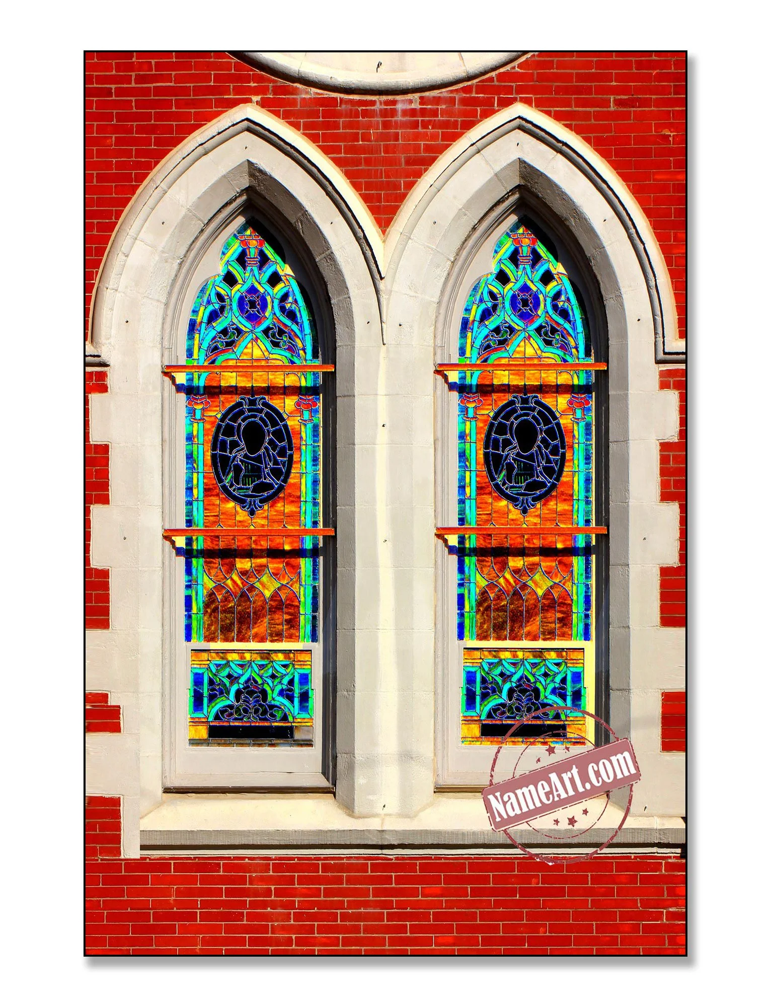 Two tall stained glass windows with colorful geometric and floral patterns set in a red brick church wall.