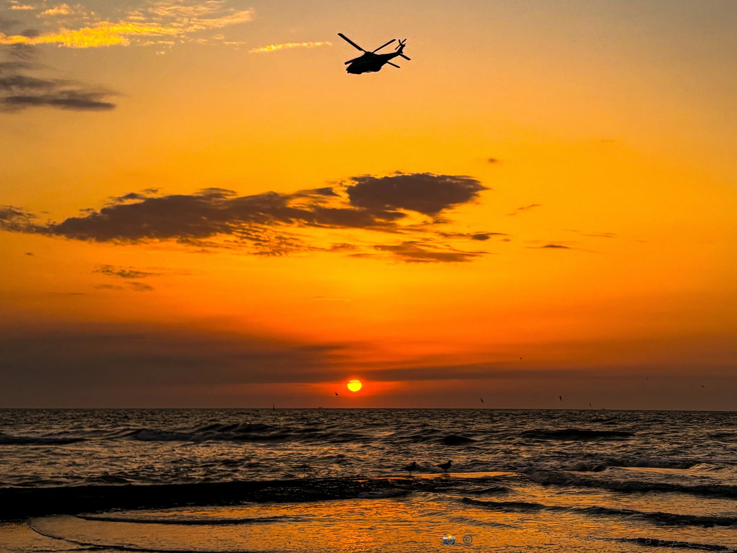 Helicopter flying into the sunset over the ocean