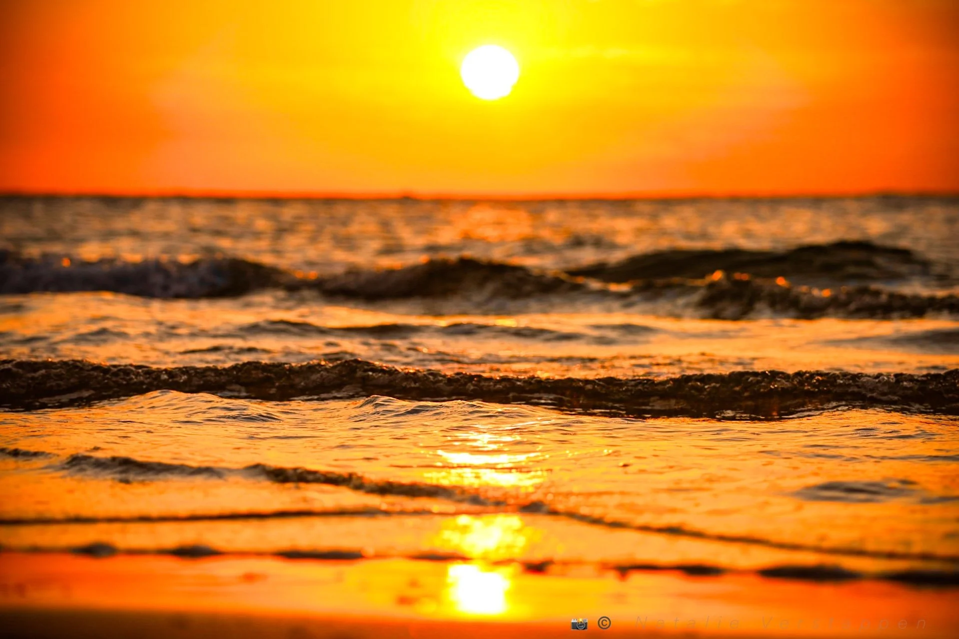 Sunset at the beach reflecting over the incoming watersurface