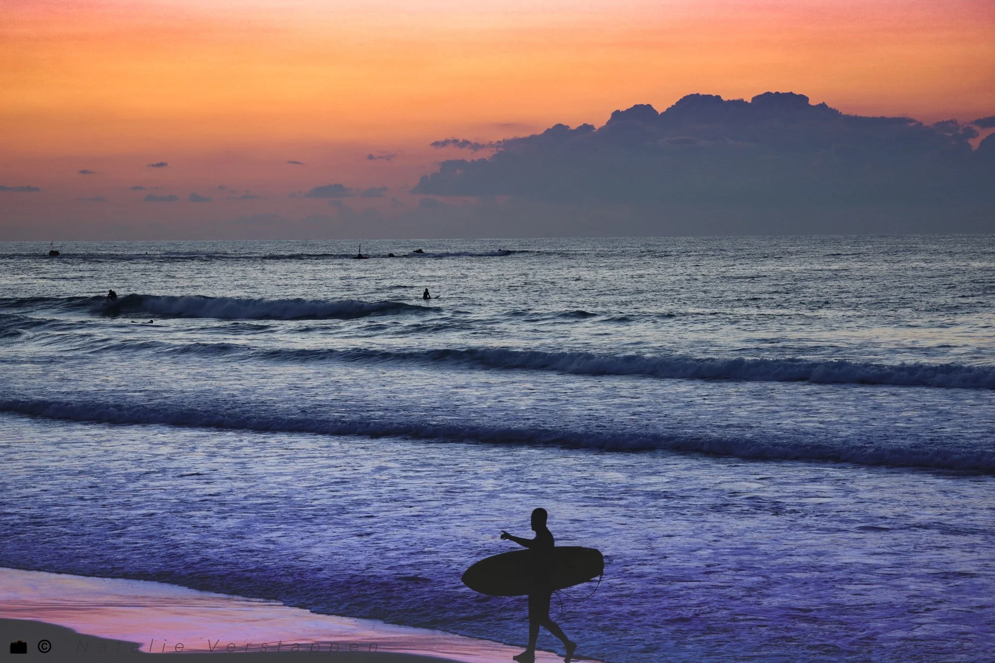 Surfer coming out of the ocean cover in the soft afterglow of the sunset