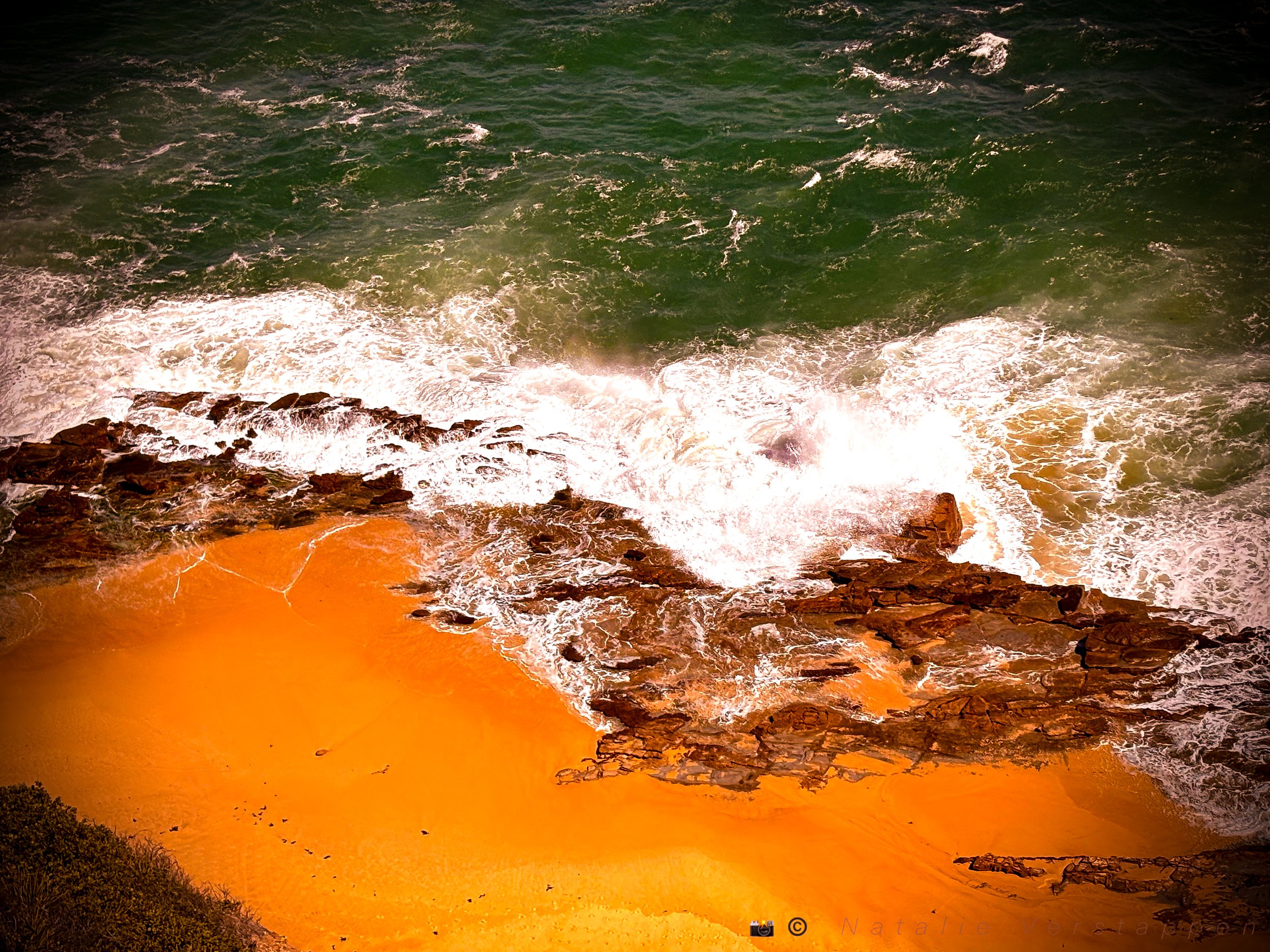 Green water, orange sand, an ocean coming to shore