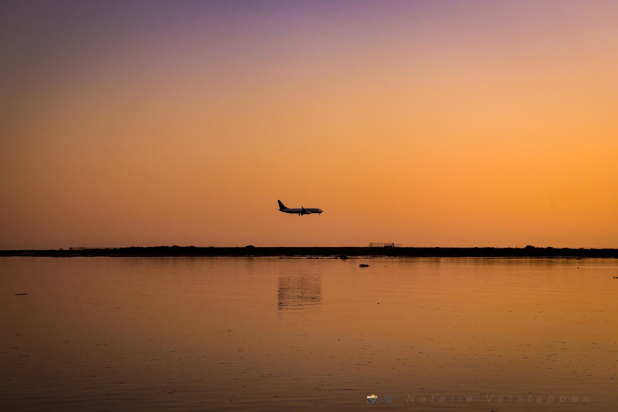 Flight landing over the ocean covered in the golden light of the sunset