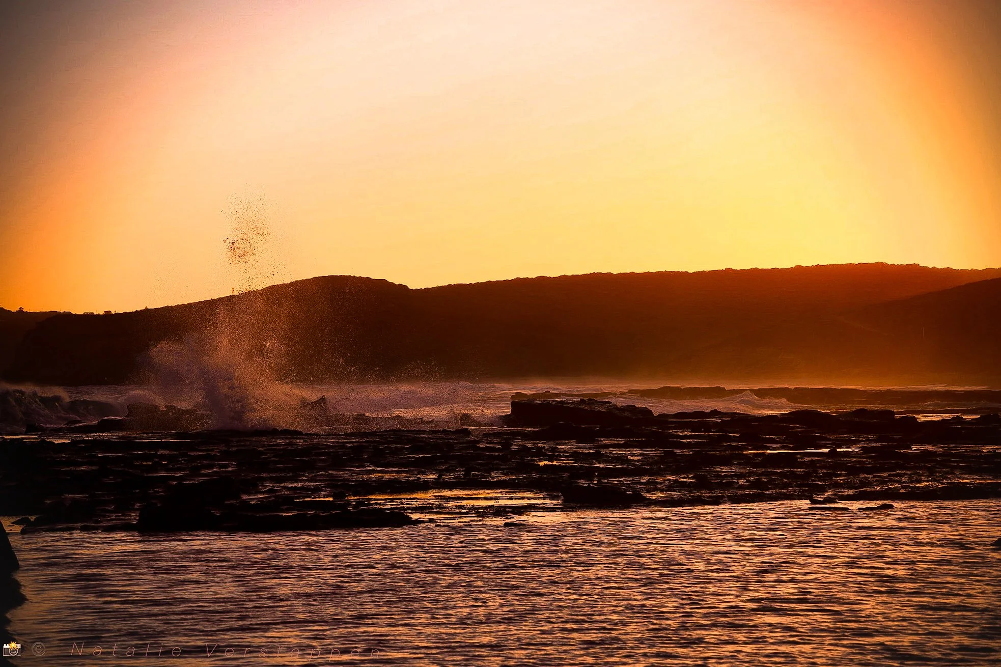 Golden sunset over the waves crashing the shore