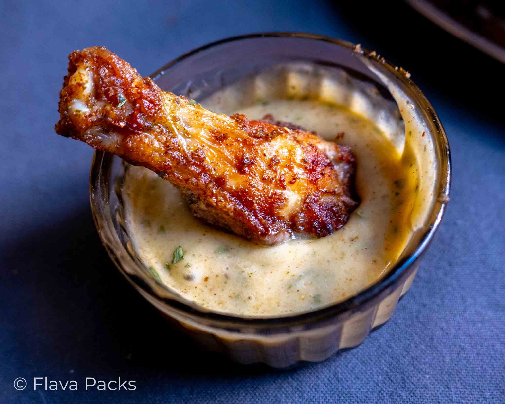 A single Air Fryer Jerk Chicken Wing in a pot of jerk mayonnaise