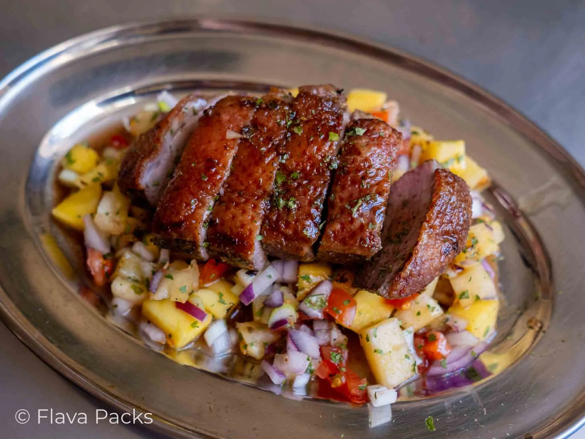 Jerk Duck Breast with Pineapple & Mango Salsa on a stainless steel dish