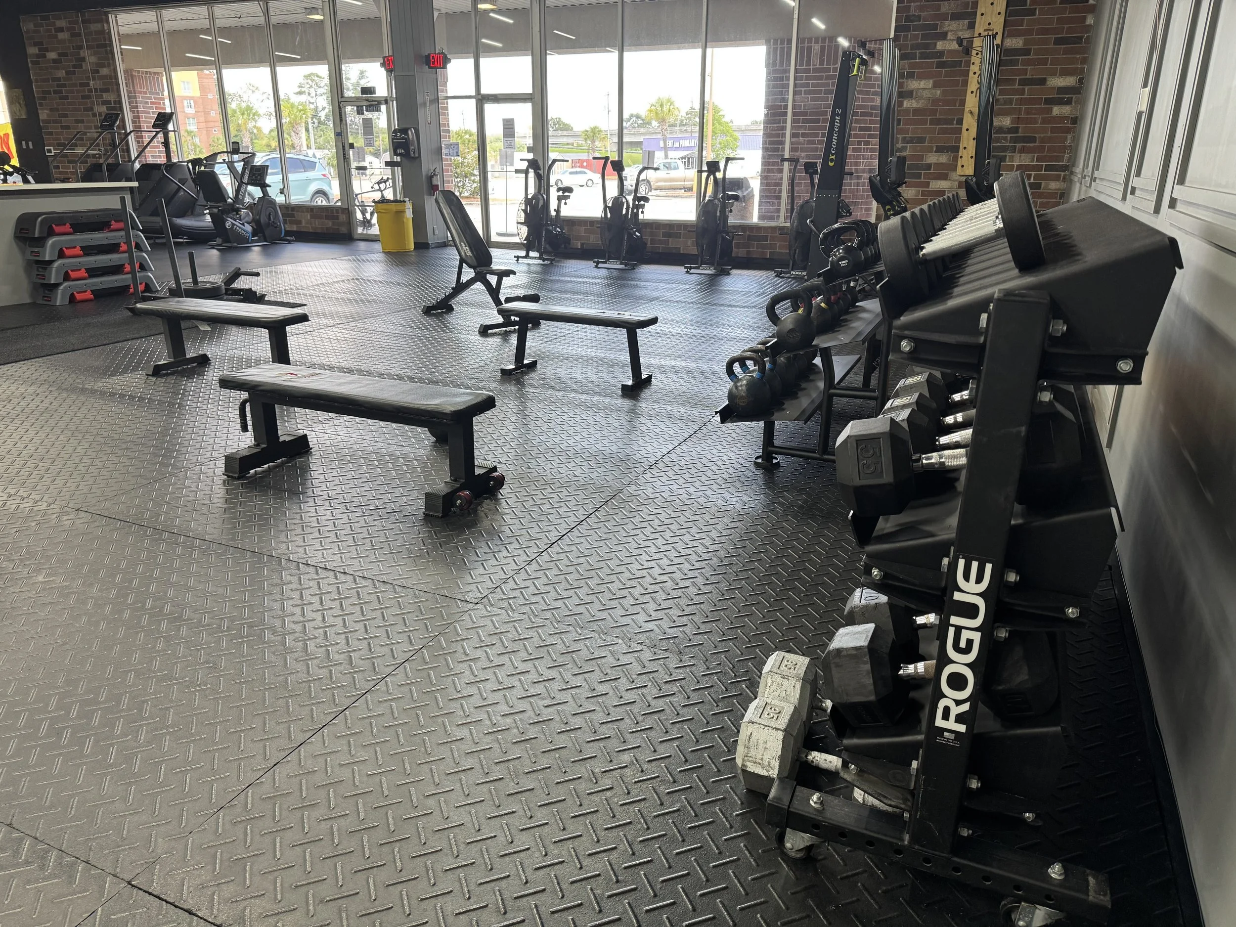 Spacious strength training floor with Rogue dumbbells, benches, kettlebells, and cardio equipment at Forge CHS gym in West Ashley Charleston SC