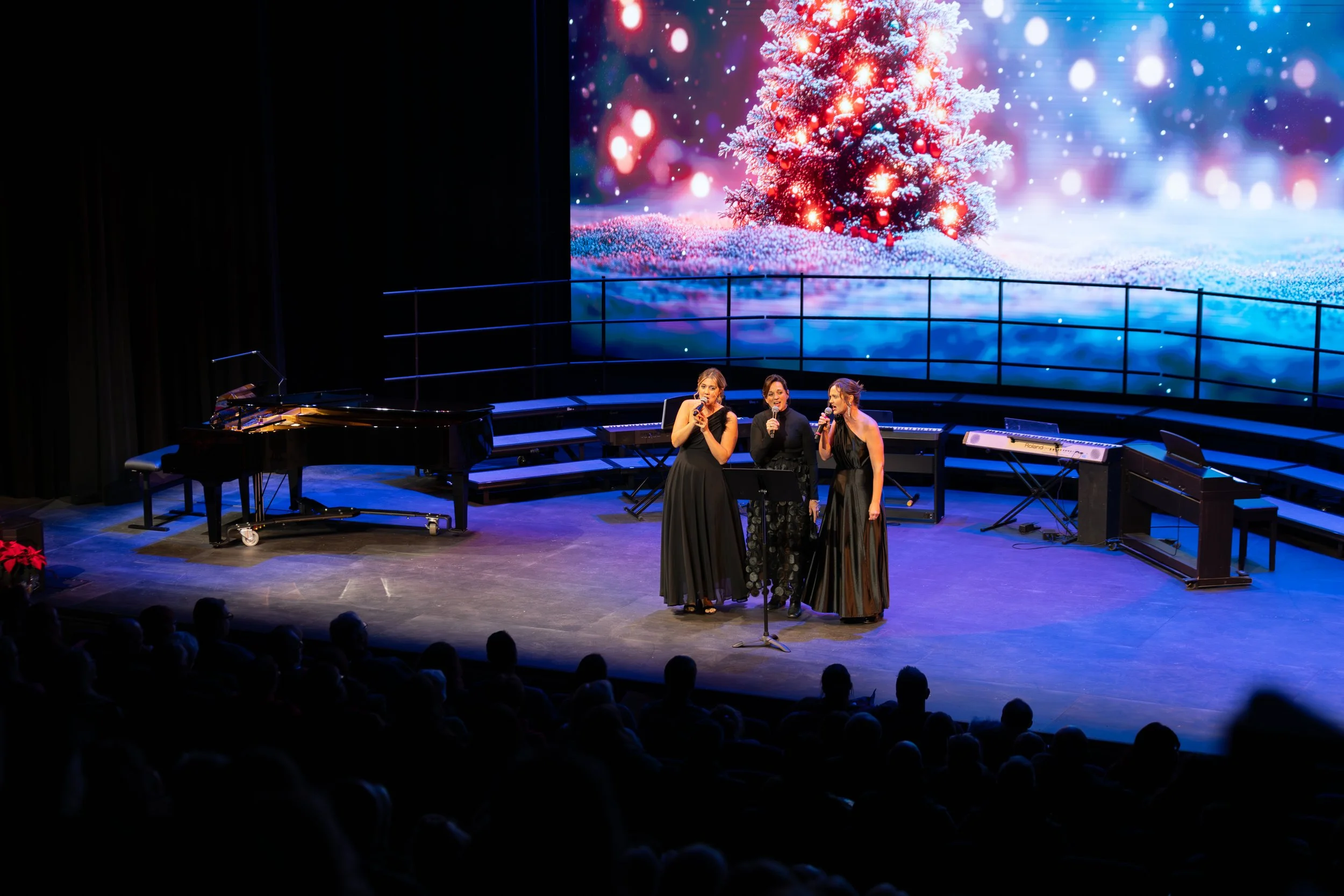 A female trio singing at a Christmas concert in the RiverPlace performance hall