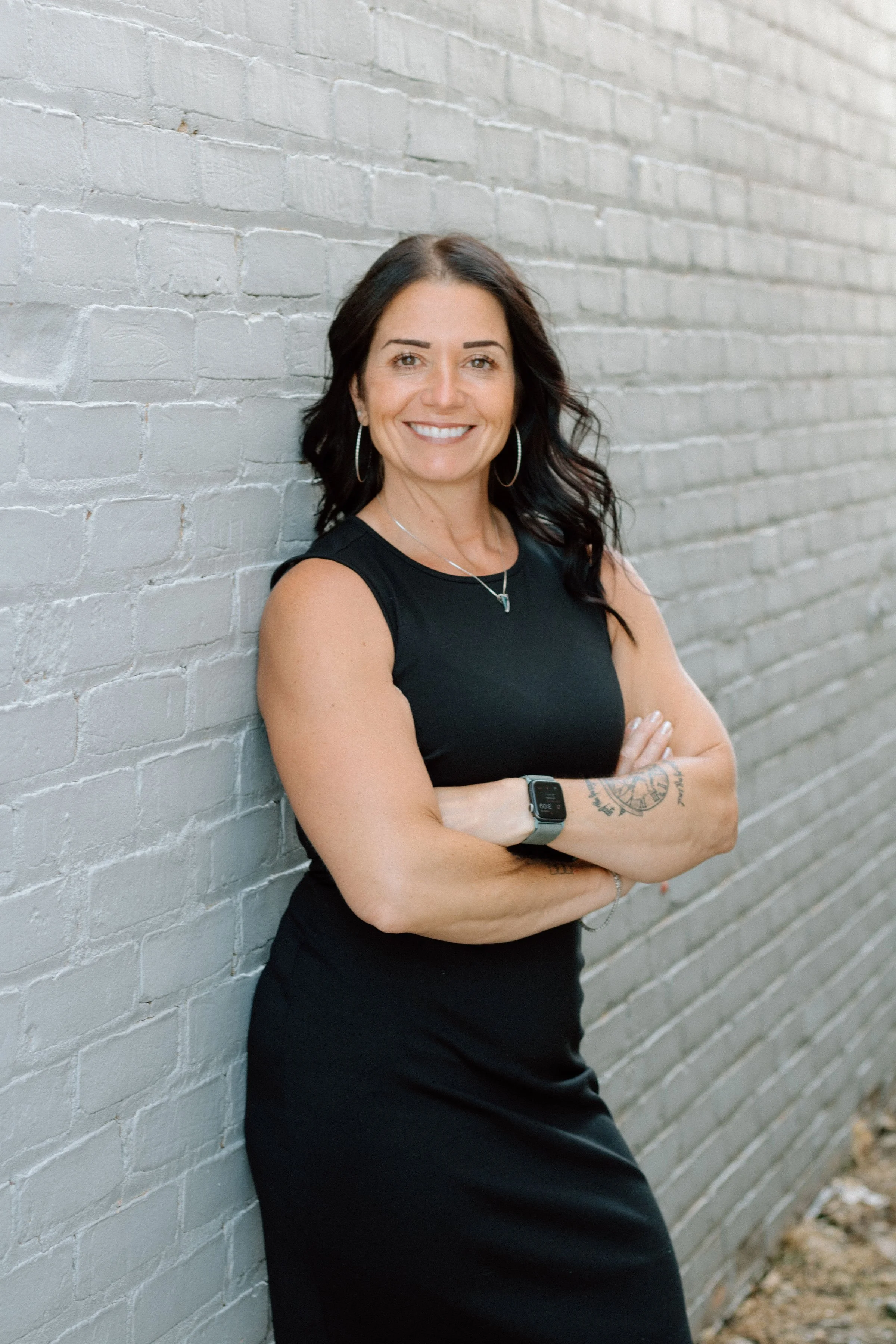 an image of Tara Wiskow standing with arms folded against a wall