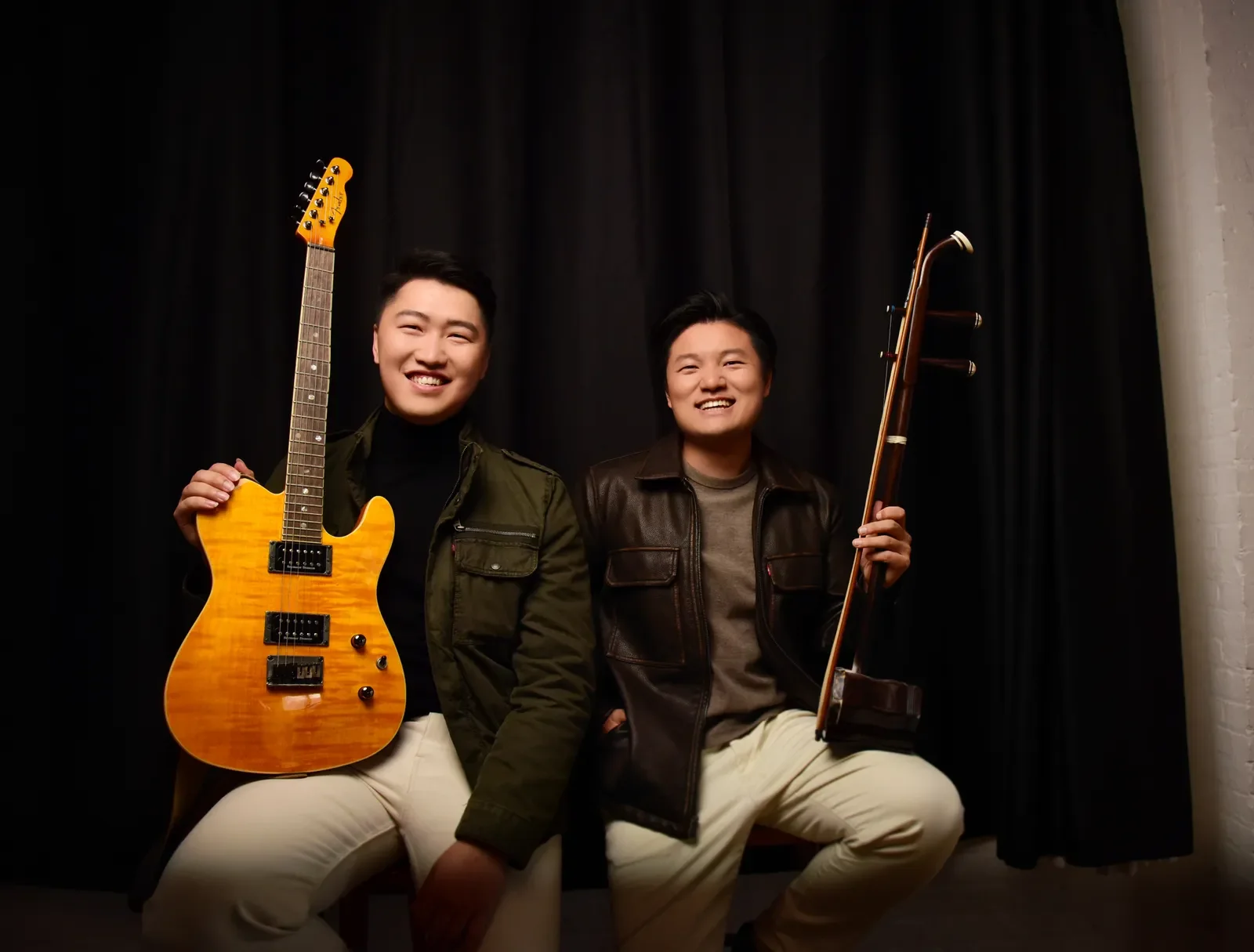a photo of Acrostrum musicians, two men holding string instruments and smiling