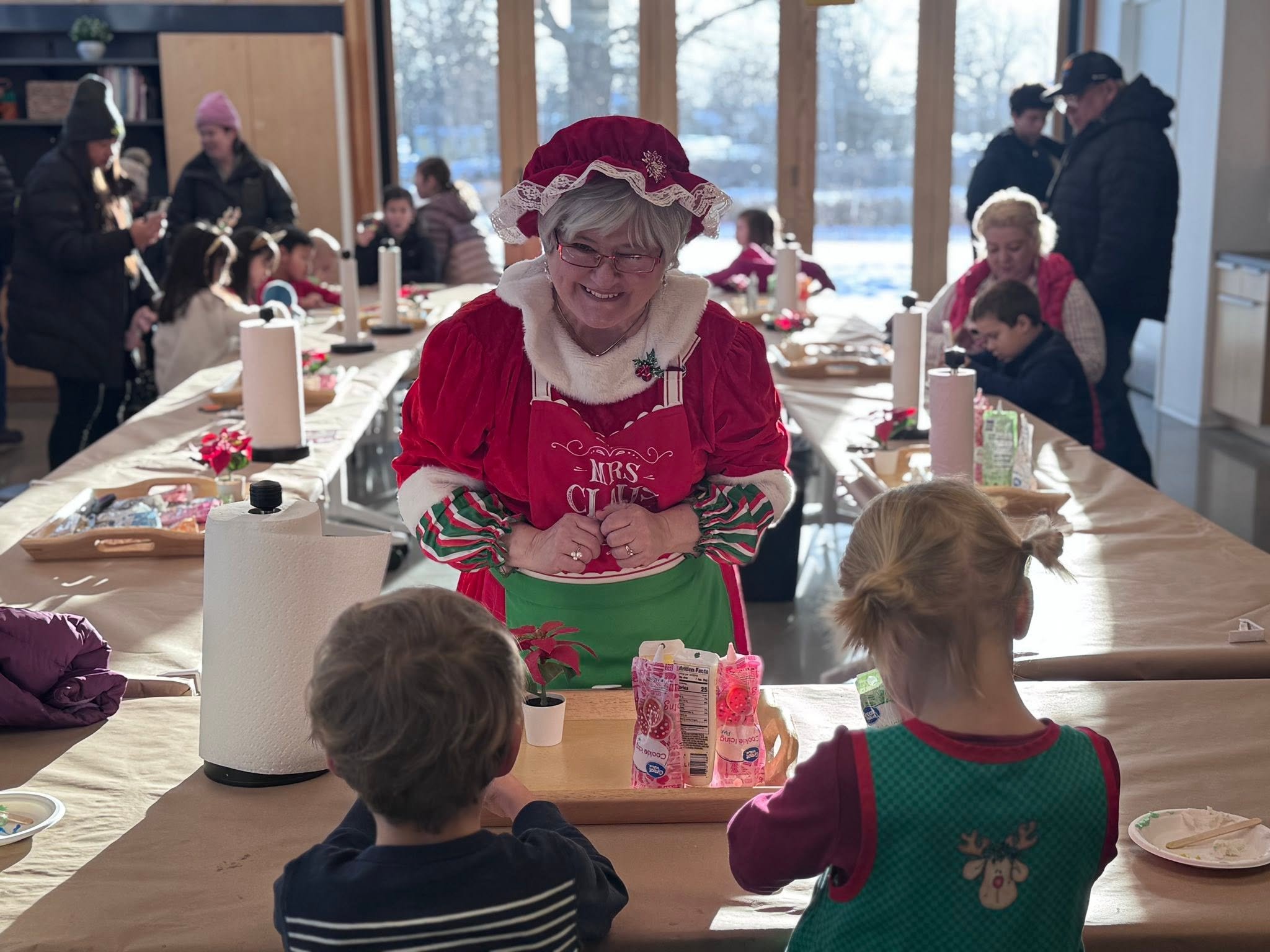 Mrs. Claus decorating cookies with kids