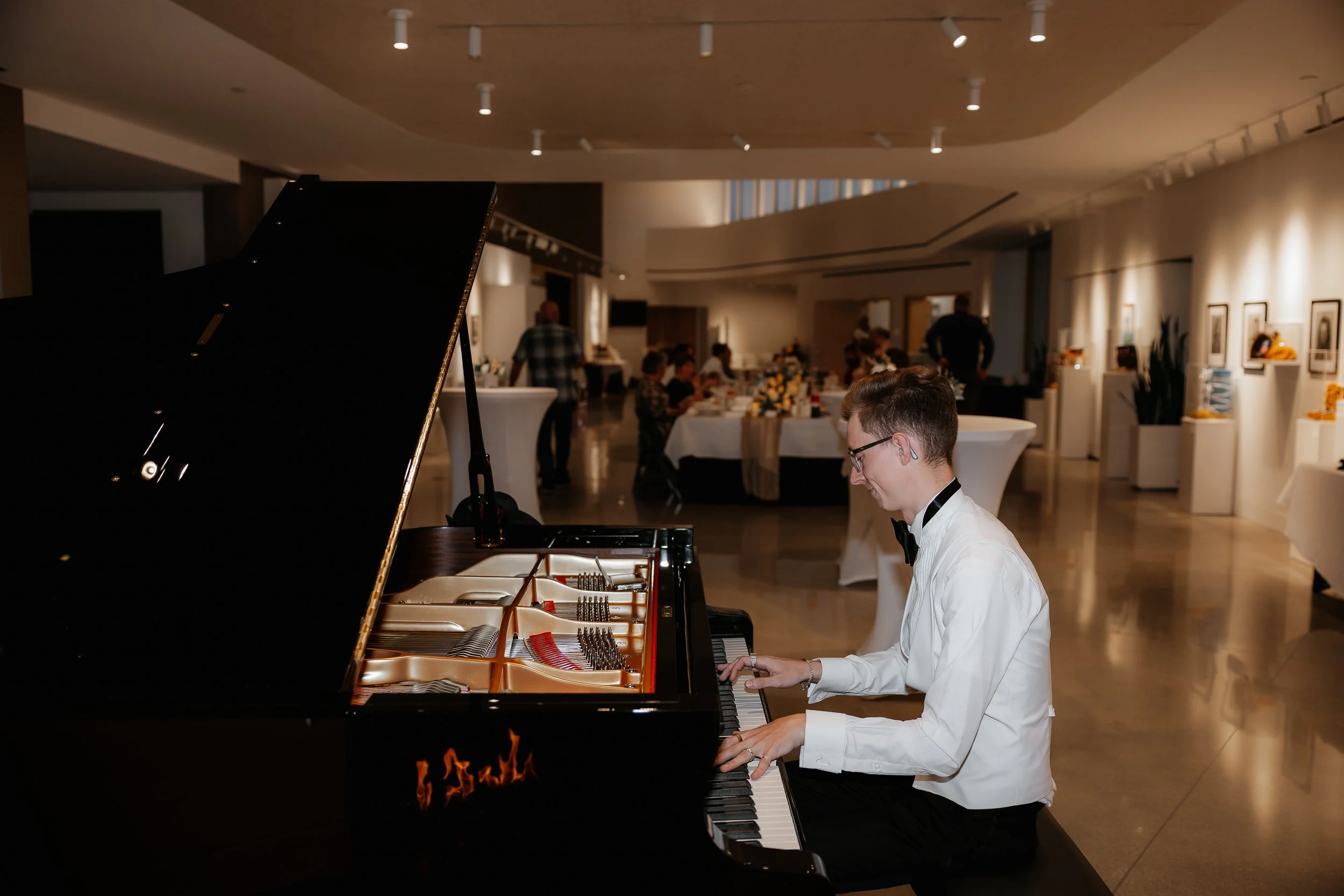 a pianist playing the grand piano at an event in the RiverPlace gallery