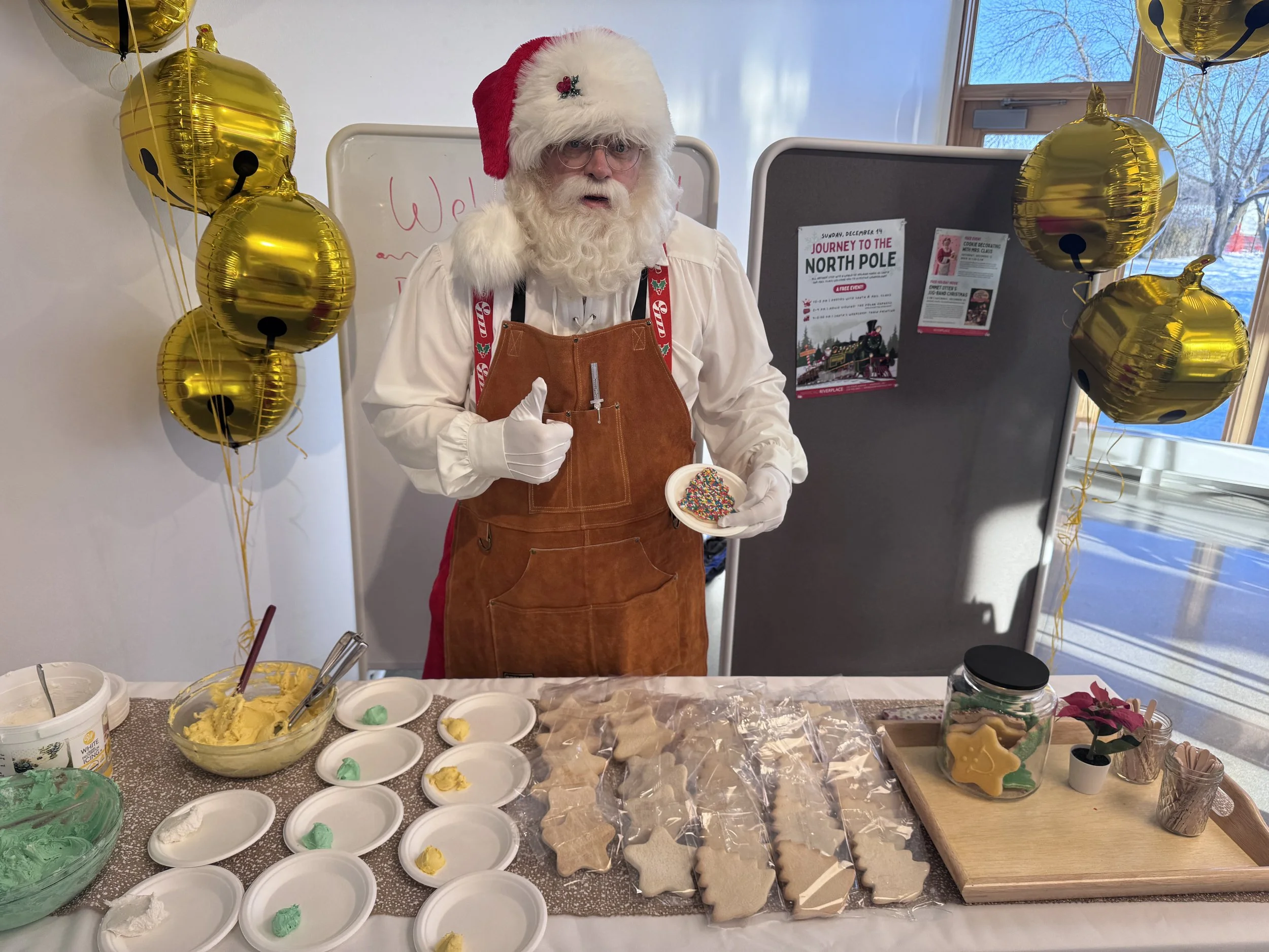 a photo Santa next to cookies to be decorated