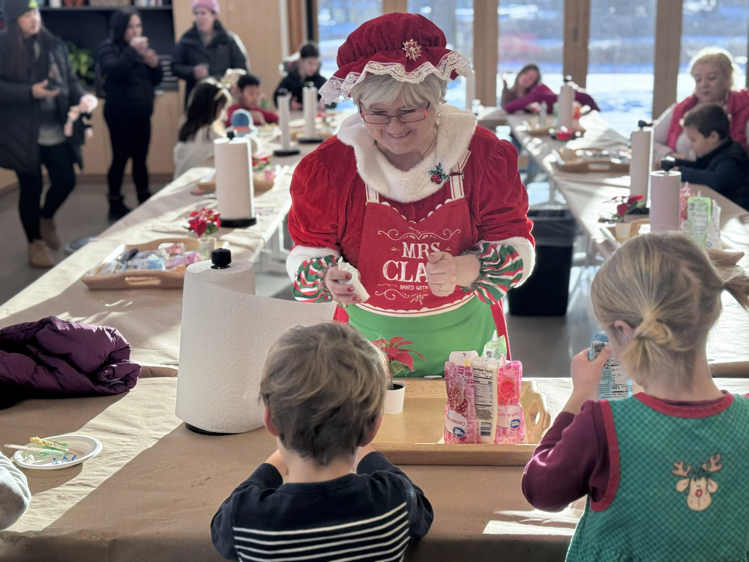 a photo of Mrs. Claus decorating cookies with kids