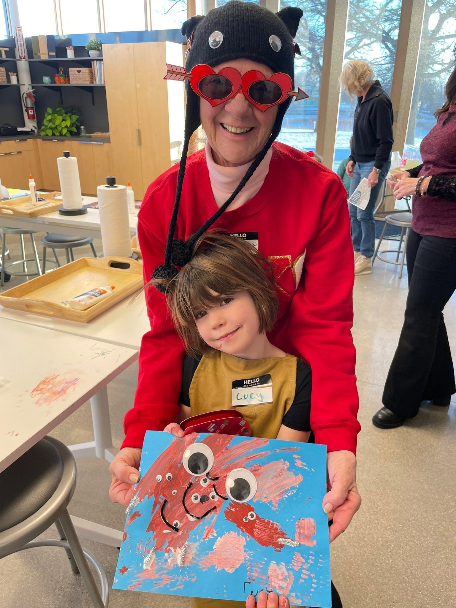 a young artist showing her artwork with a teacher dressed up for Valentine's Day