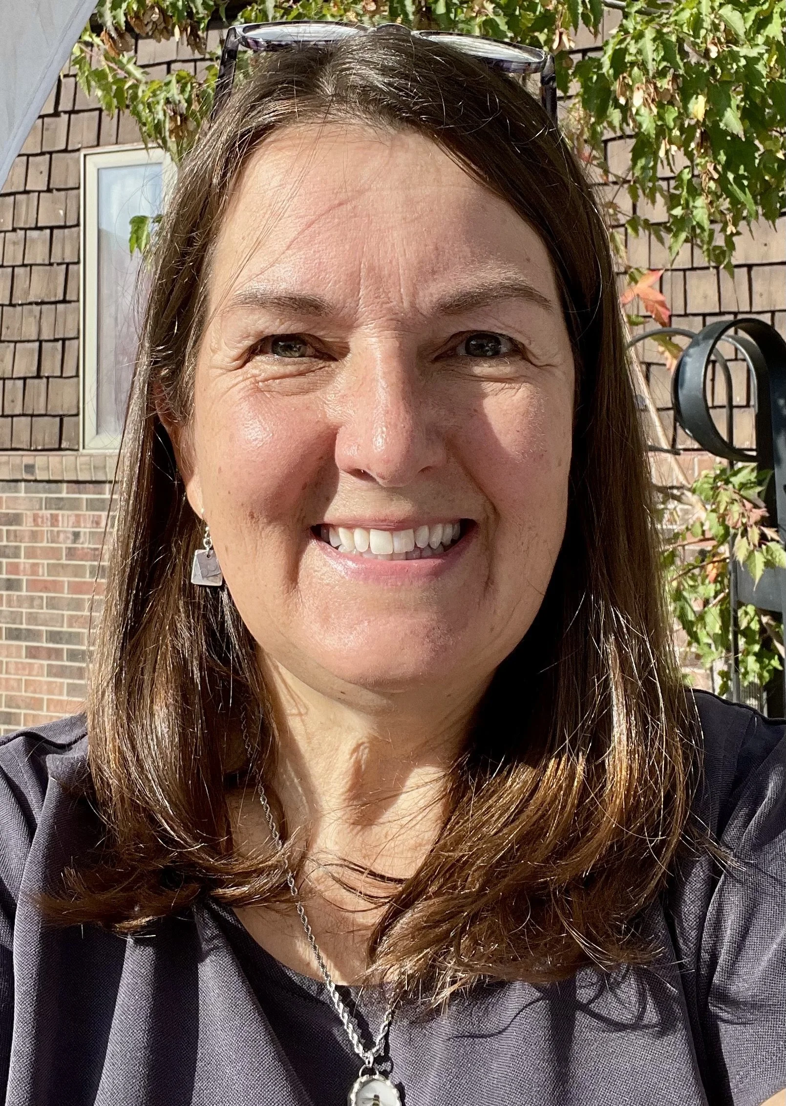 a headshot of artist Diana Manager smiling at the camera with mid-length brown hair
