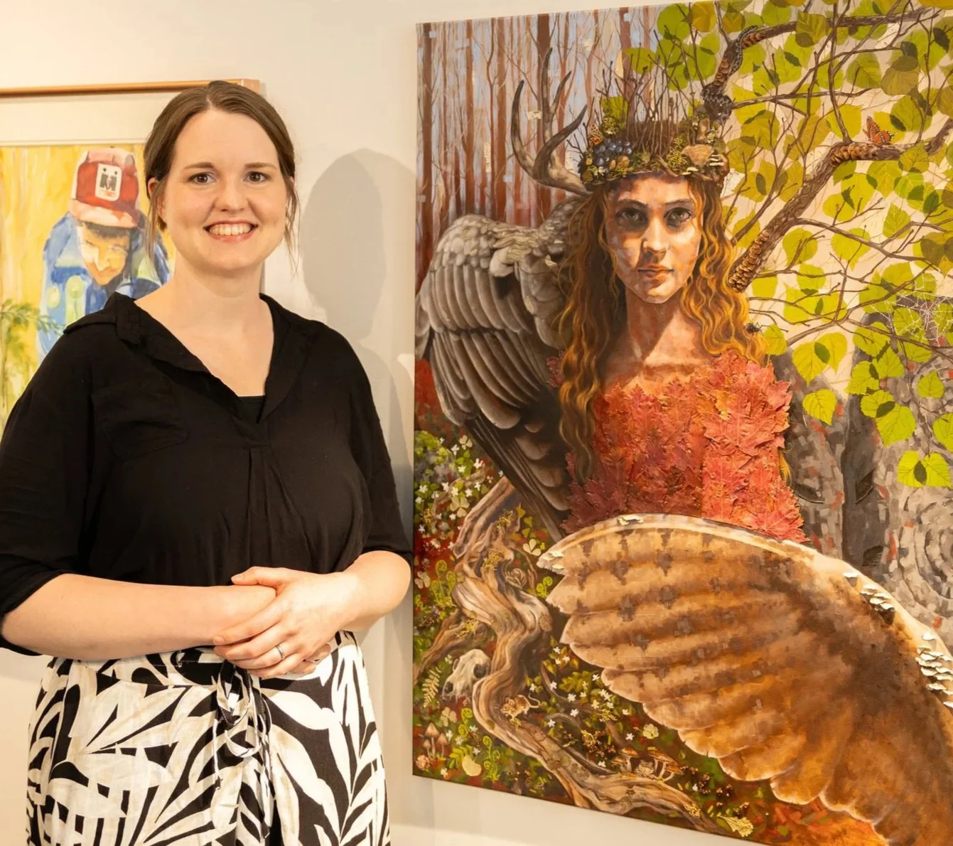 Holly Marie standing next to her painting of a fairytale woman