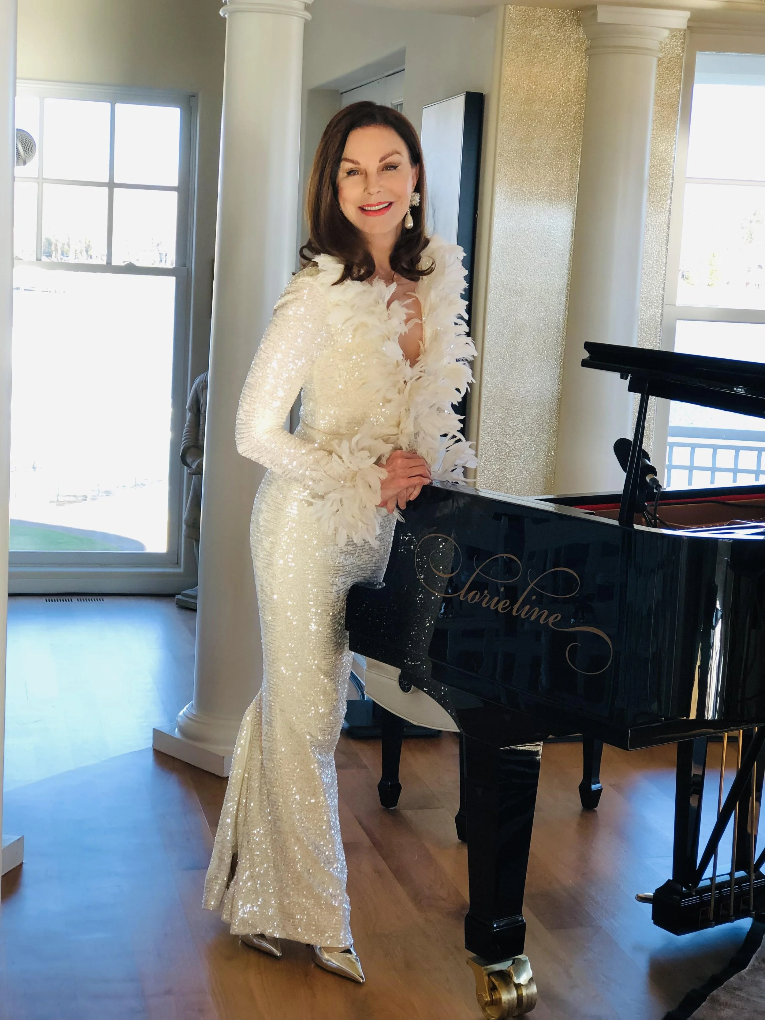 an image of musician Lorie Line standing next to her piano wearing a sparkly white dress