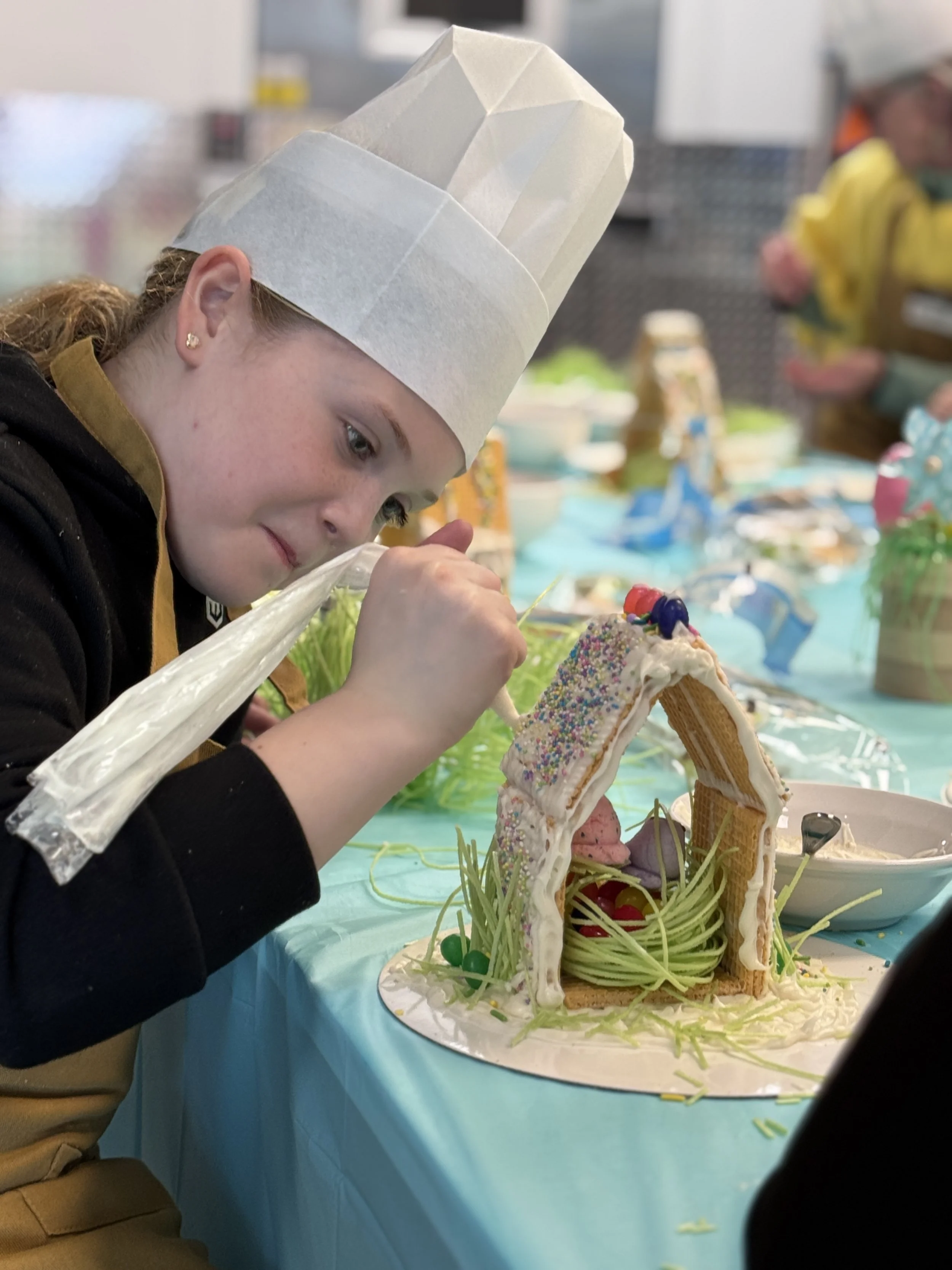 a young student decorating an Easter house in the RiverPlace commercial kitchen