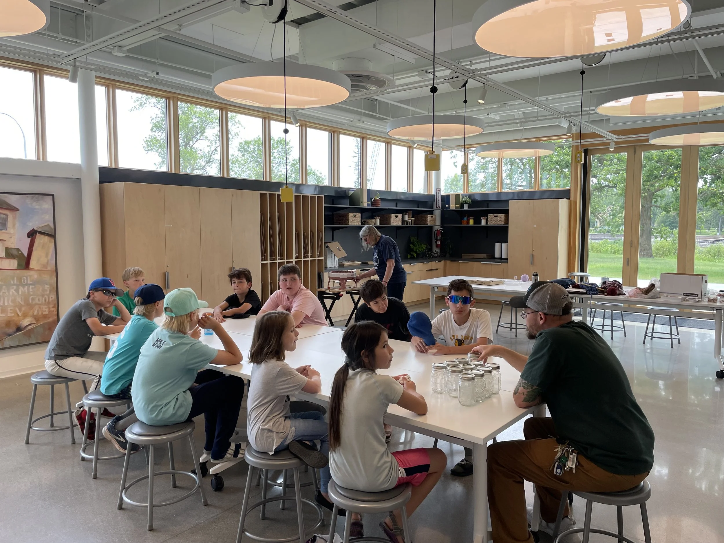 a group of kids sitting in an art classroom learning about canning
