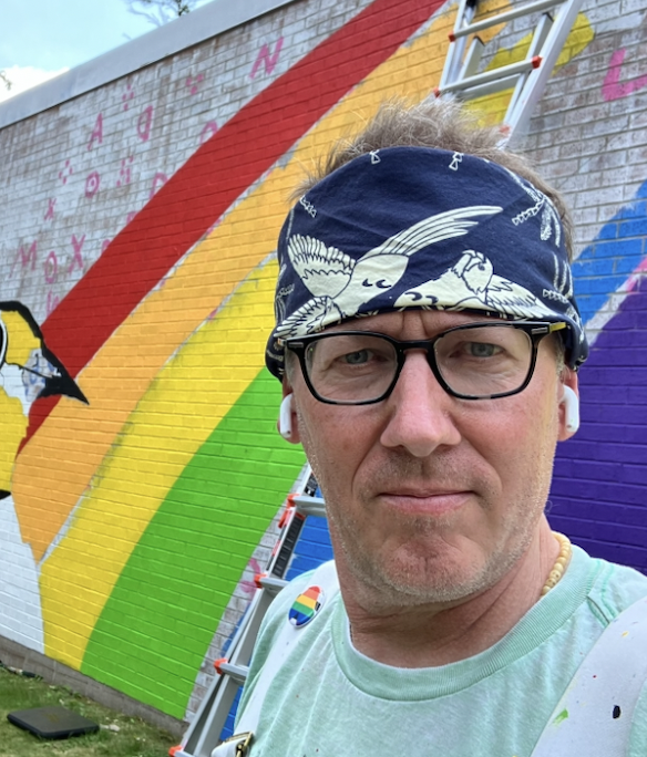 a selfie of Trey Everett in front of a rainbow mural