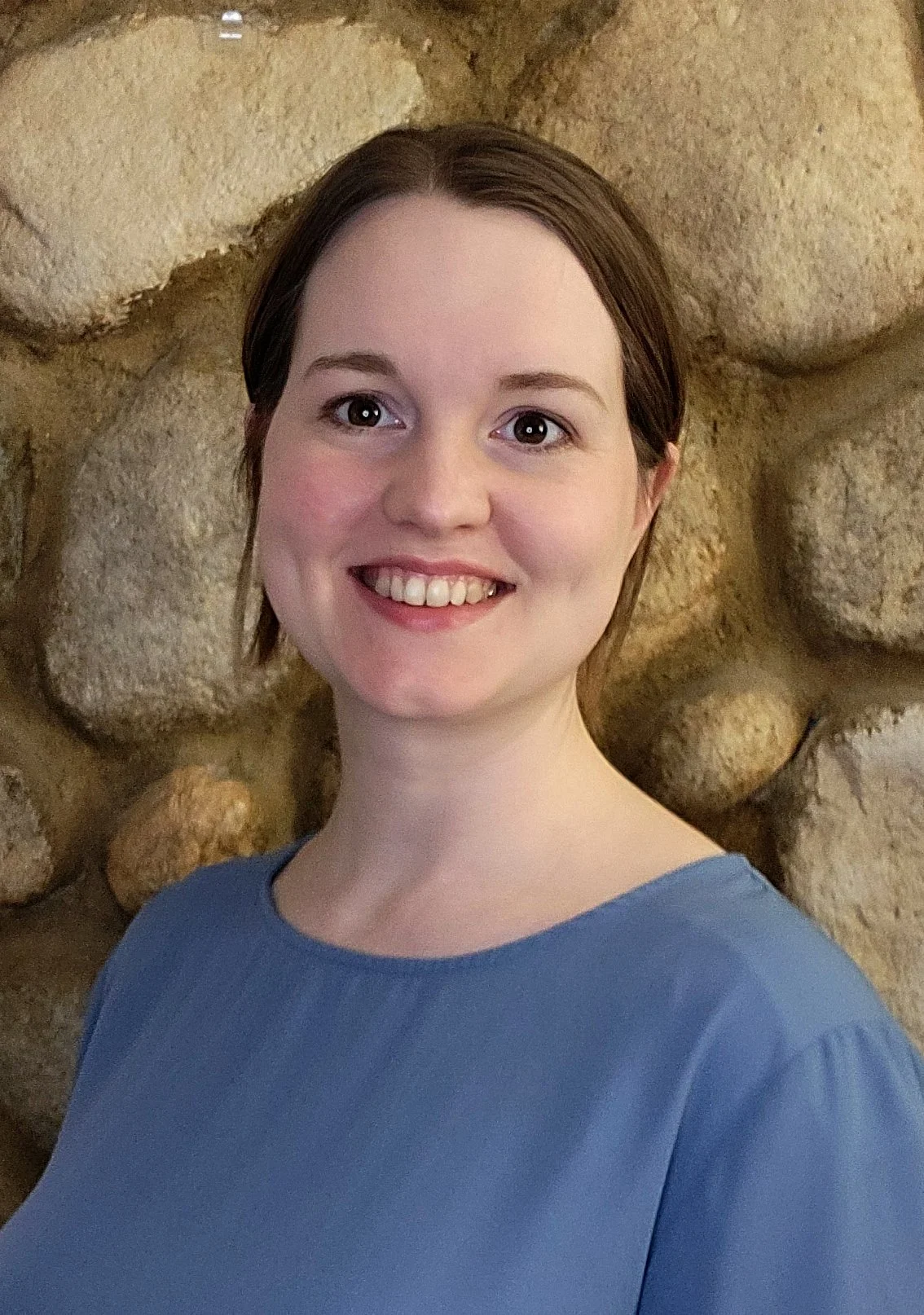 a head shot of artist Holly Marie Crowther smiling into the camera with brown eyes and hair