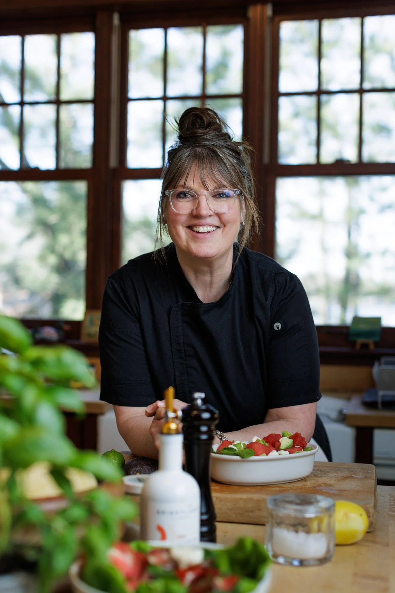 a headshot of chef Kara Super-Peterson at a table with foraged ingredients
