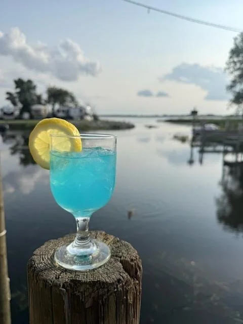 a blue cocktail on a dock by a river