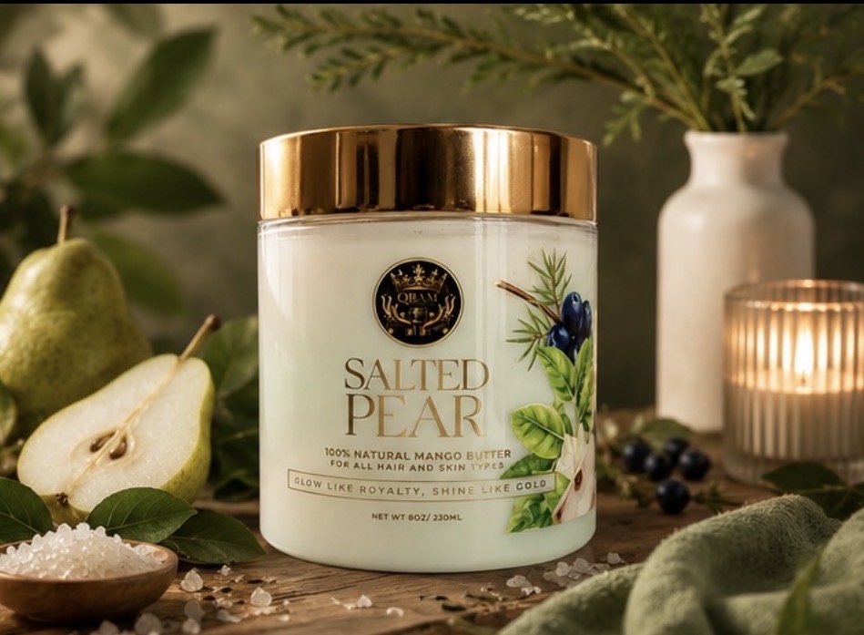Container of salted pear flavored hair and skin butter, surrounded by pears, leaves, and a candlelit arrangement.