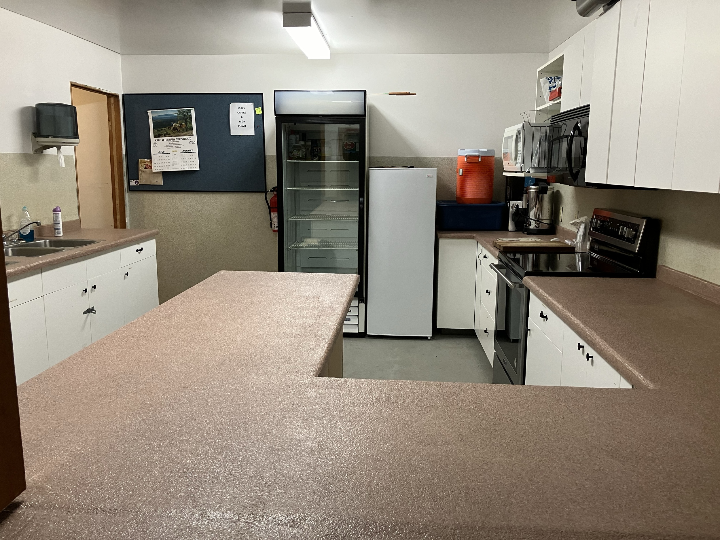 Kitchen with full stove, microwave, small upright freezer and full commercial refrigerator, 2 sinks (no dishwasher)