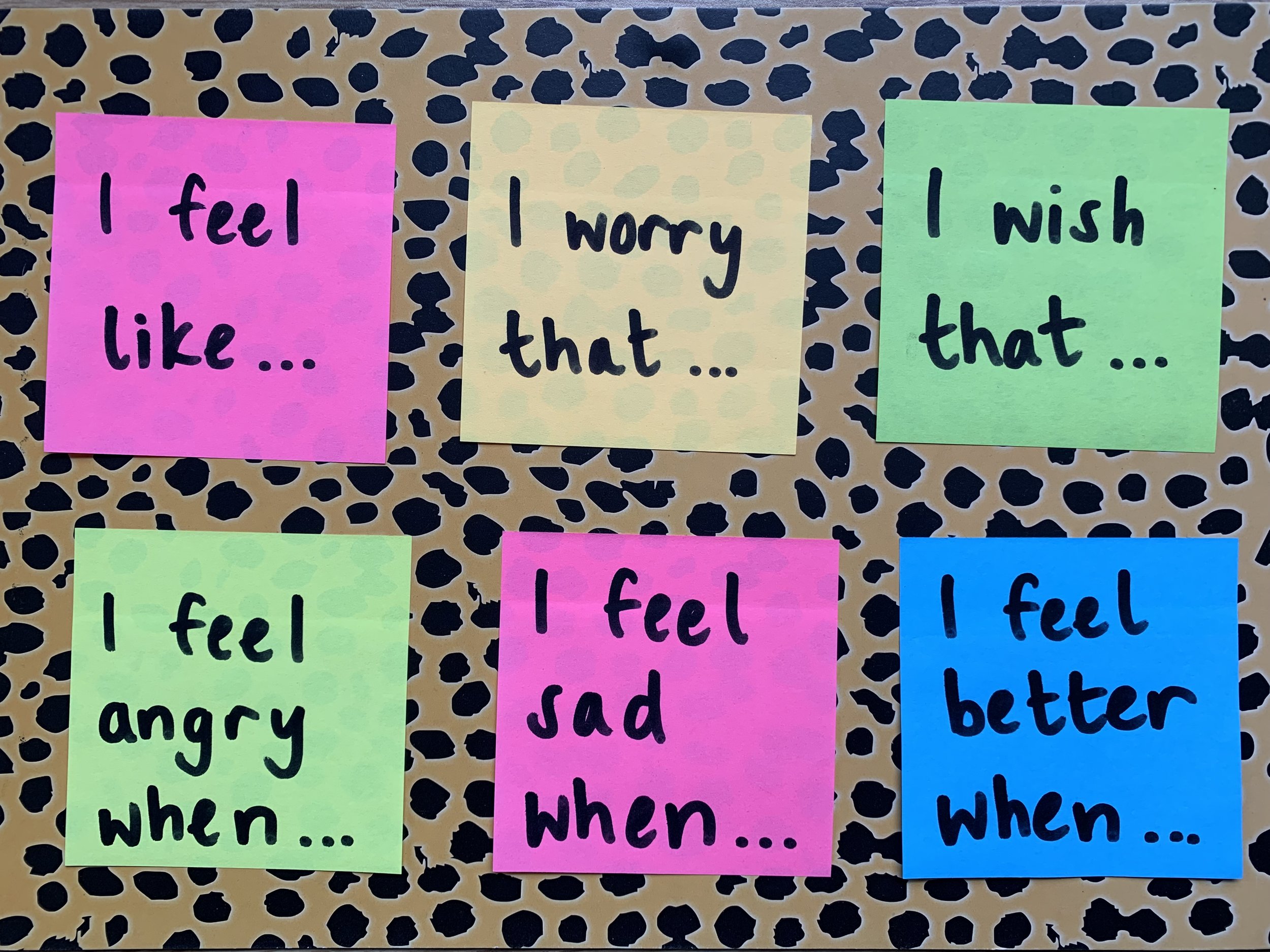 A photo of different coloured post it notes with written feeling prompts on a leopard print background