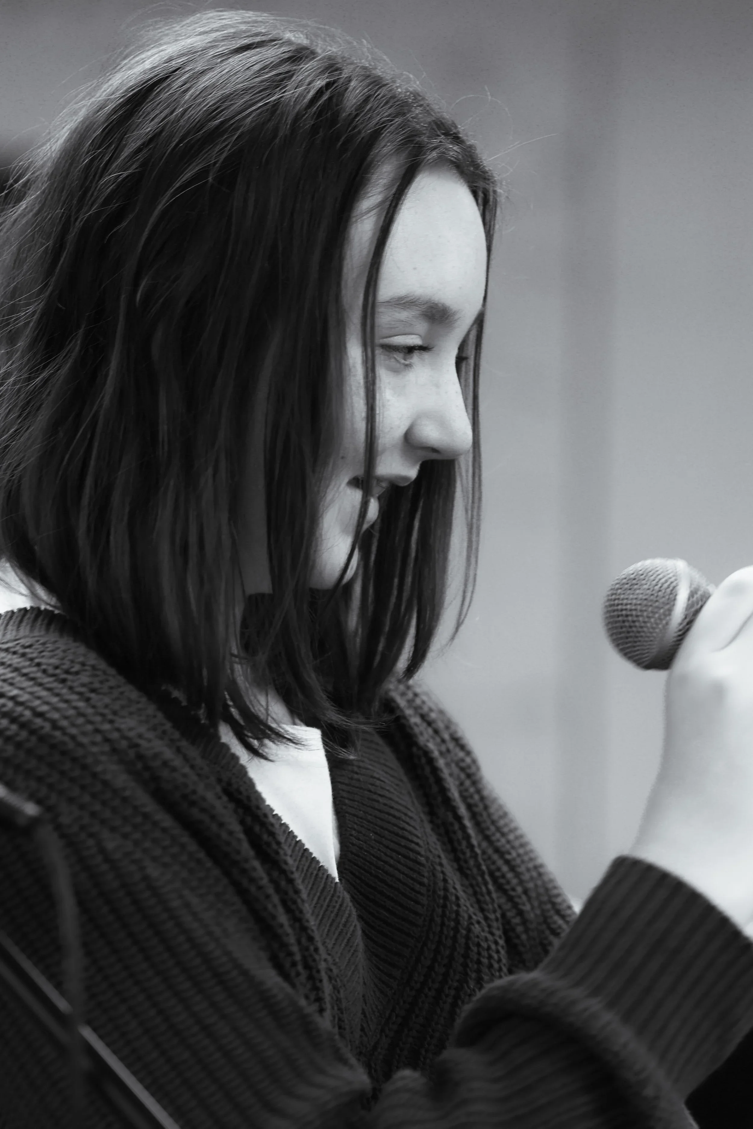 Black and white photo of a teenage girl, smiling and holding a microphone.