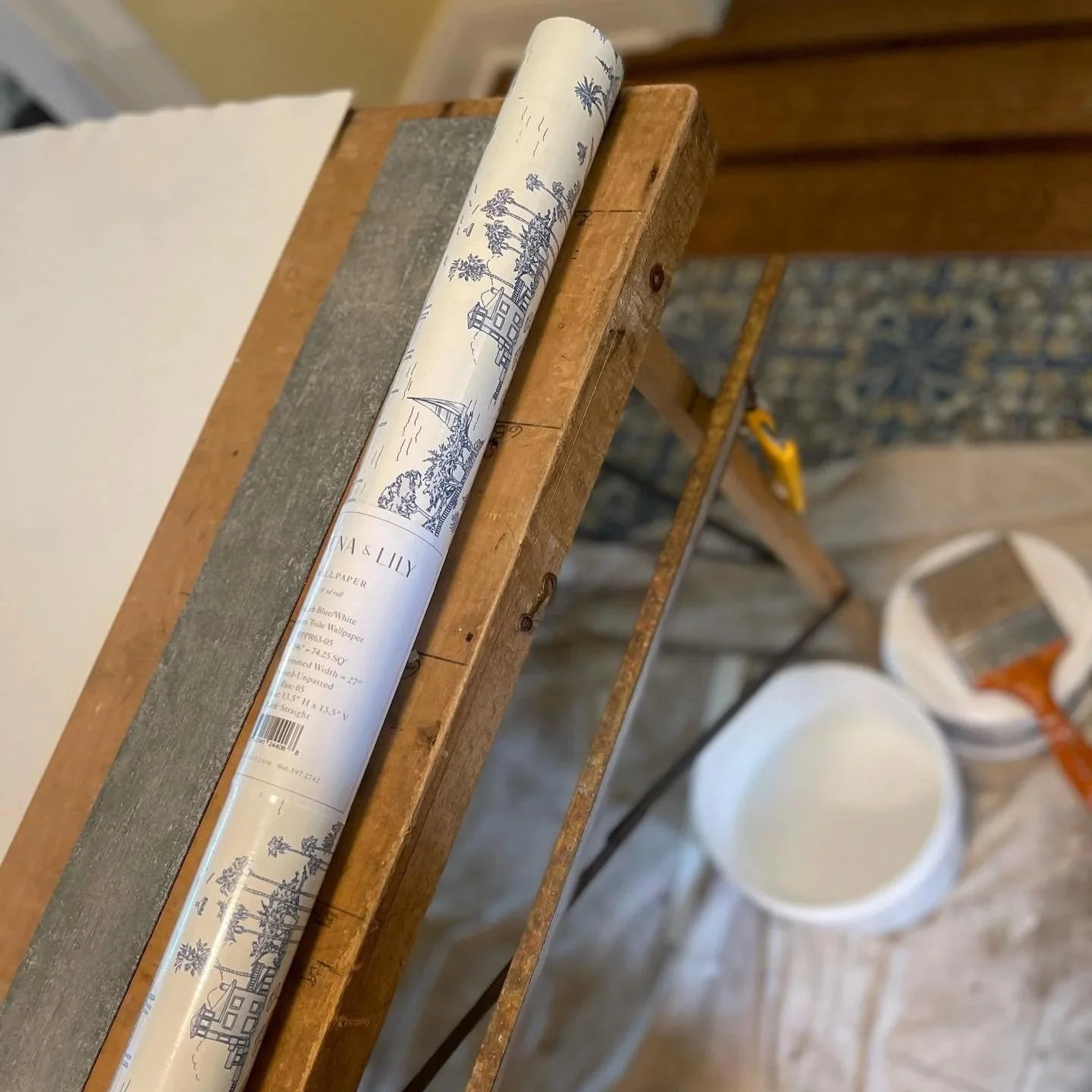 Wallpaper install site featuring table, scissors, glue, wallpaper roll, and brushes