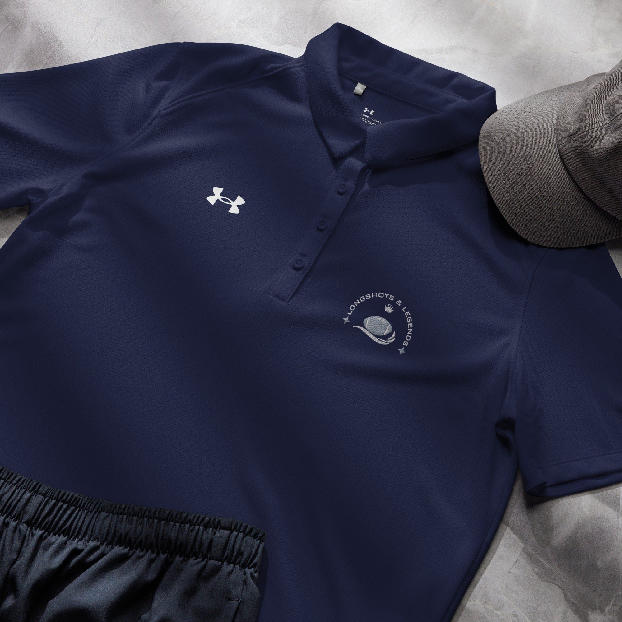 Custom embroidered women’s Under Armour® collared polo shirt with football logo in navy blue. Celebrate with the Longshots and Legends collection of athletic wear.