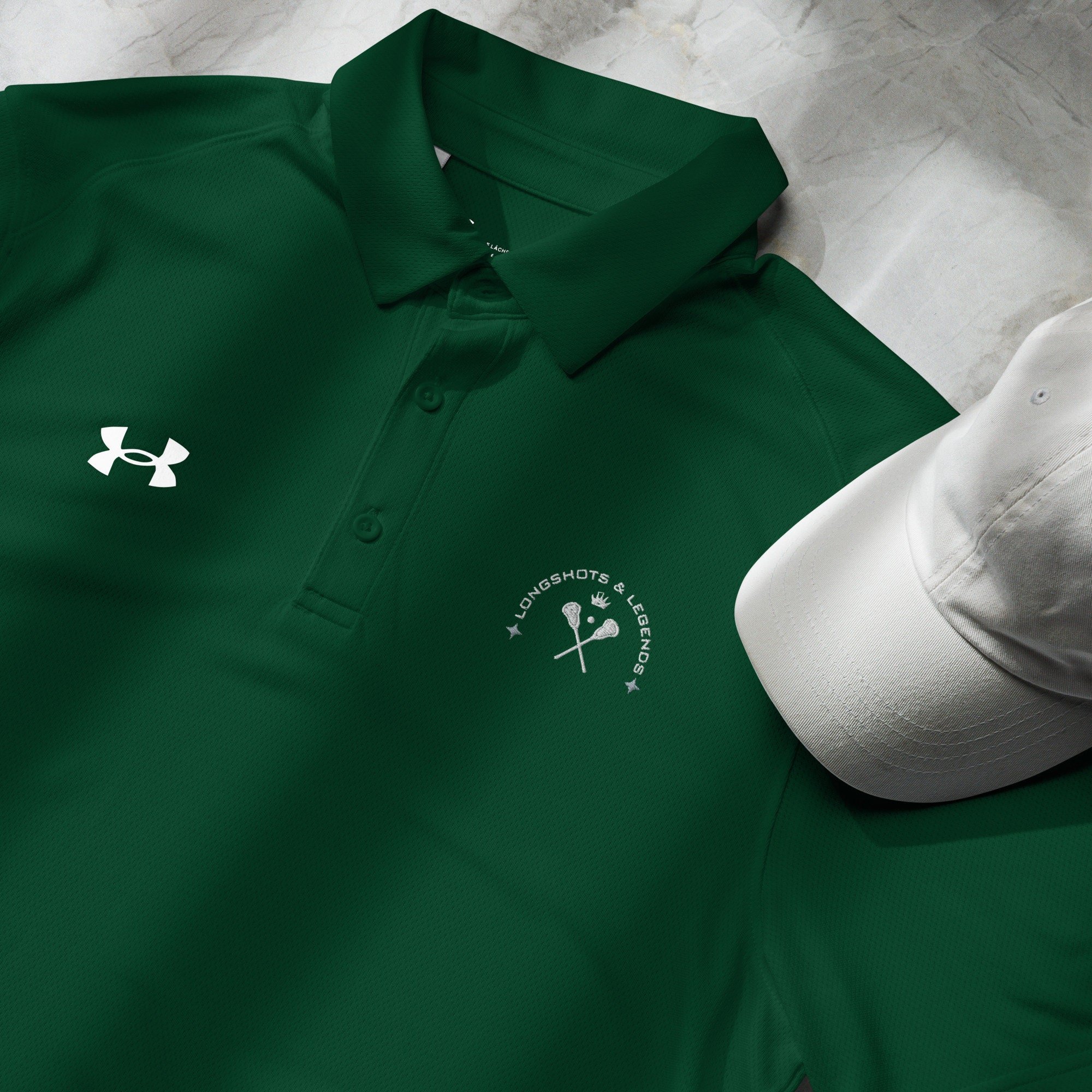 Custom embroidered men’s Under Armour® collared polo shirt with lacrosse logo in spruce green. Celebrate with the Longshots and Legends collection of athletic wear.