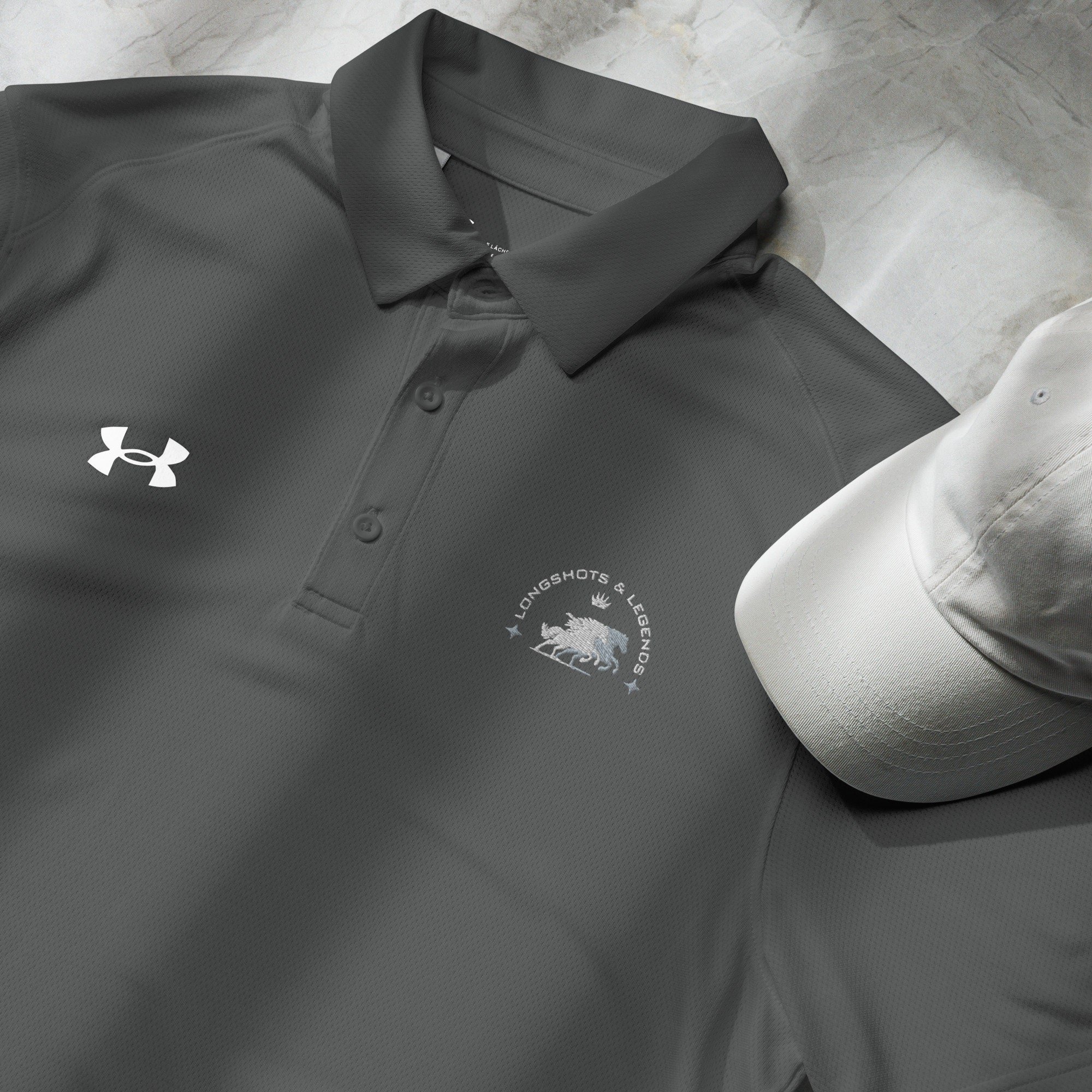 Custom embroidered men’s Under Armour® collared polo shirt with equestrian logo in dark gray. Celebrate with the Longshots and Legends collection of athletic wear.