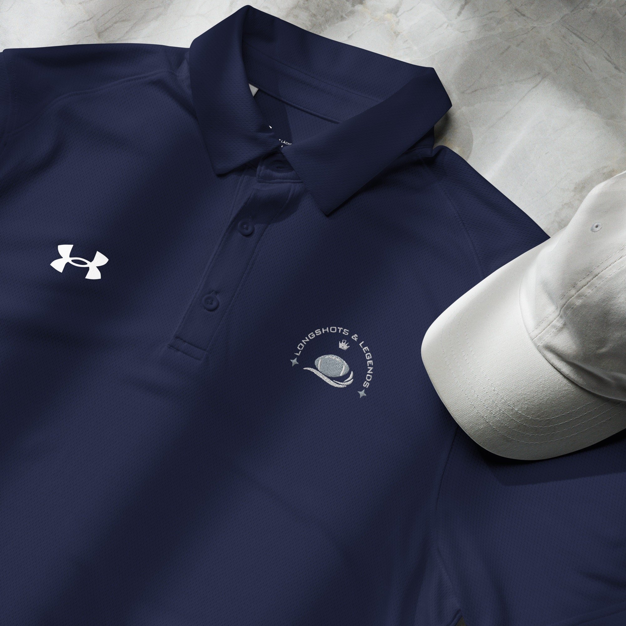 Custom embroidered men’s Under Armour® collared polo shirt with football logo in navy blue. Celebrate with the Longshots and Legends collection of athletic wear.