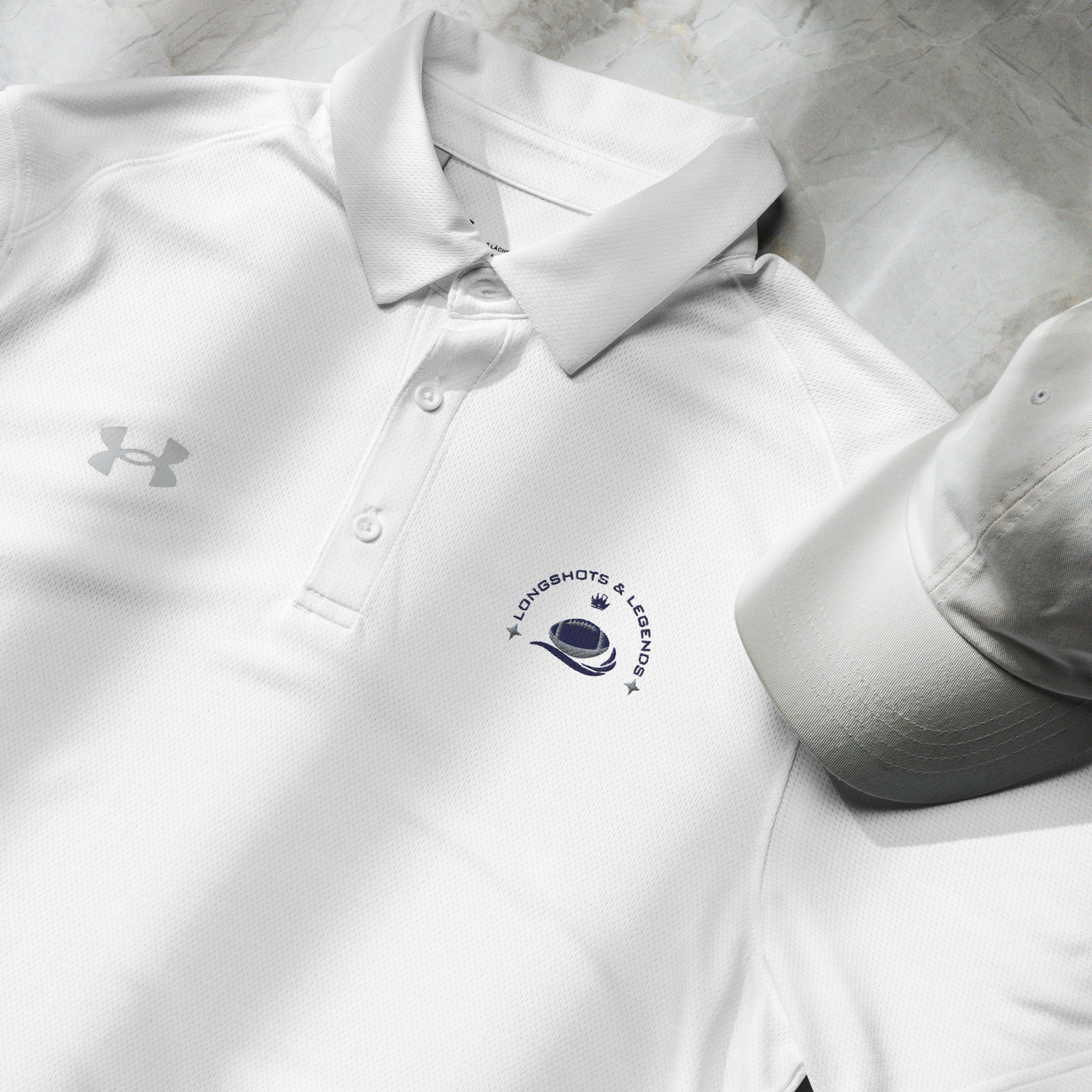 Custom embroidered men’s Under Armour® collared polo shirt with football logo in white. Celebrate with the Longshots and Legends collection of athletic wear.