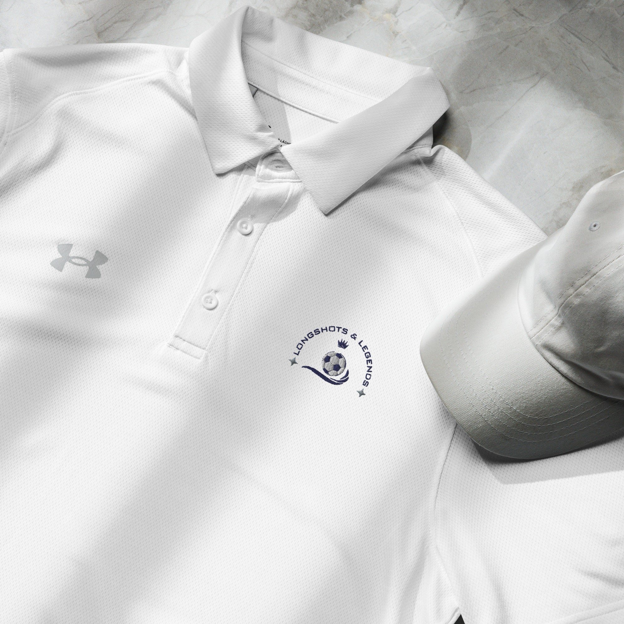 Custom embroidered men’s Under Armour® collared polo shirt with soccer logo in white. Celebrate with the Longshots and Legends collection of athletic wear.