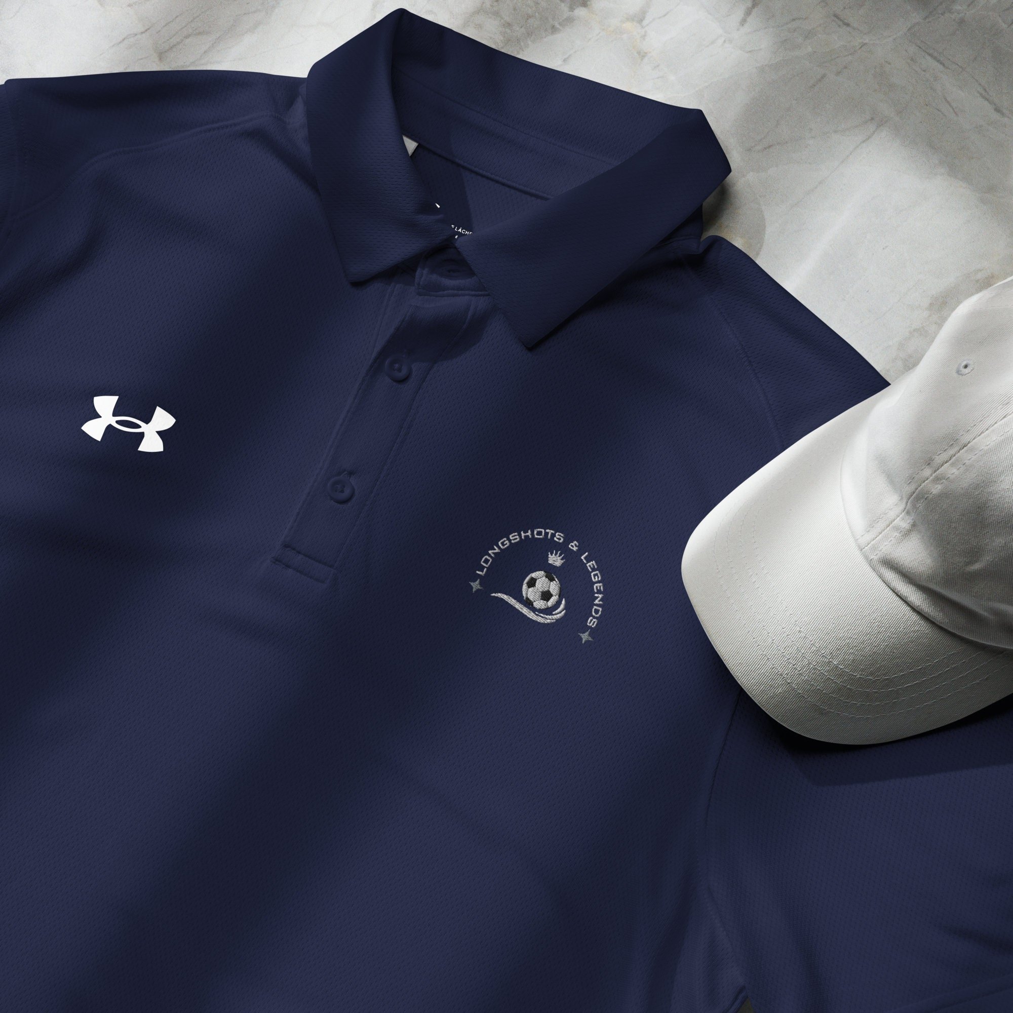 Custom embroidered men’s Under Armour® collared polo shirt with soccer logo in navy blue. Celebrate with the Longshots and Legends collection of athletic wear.