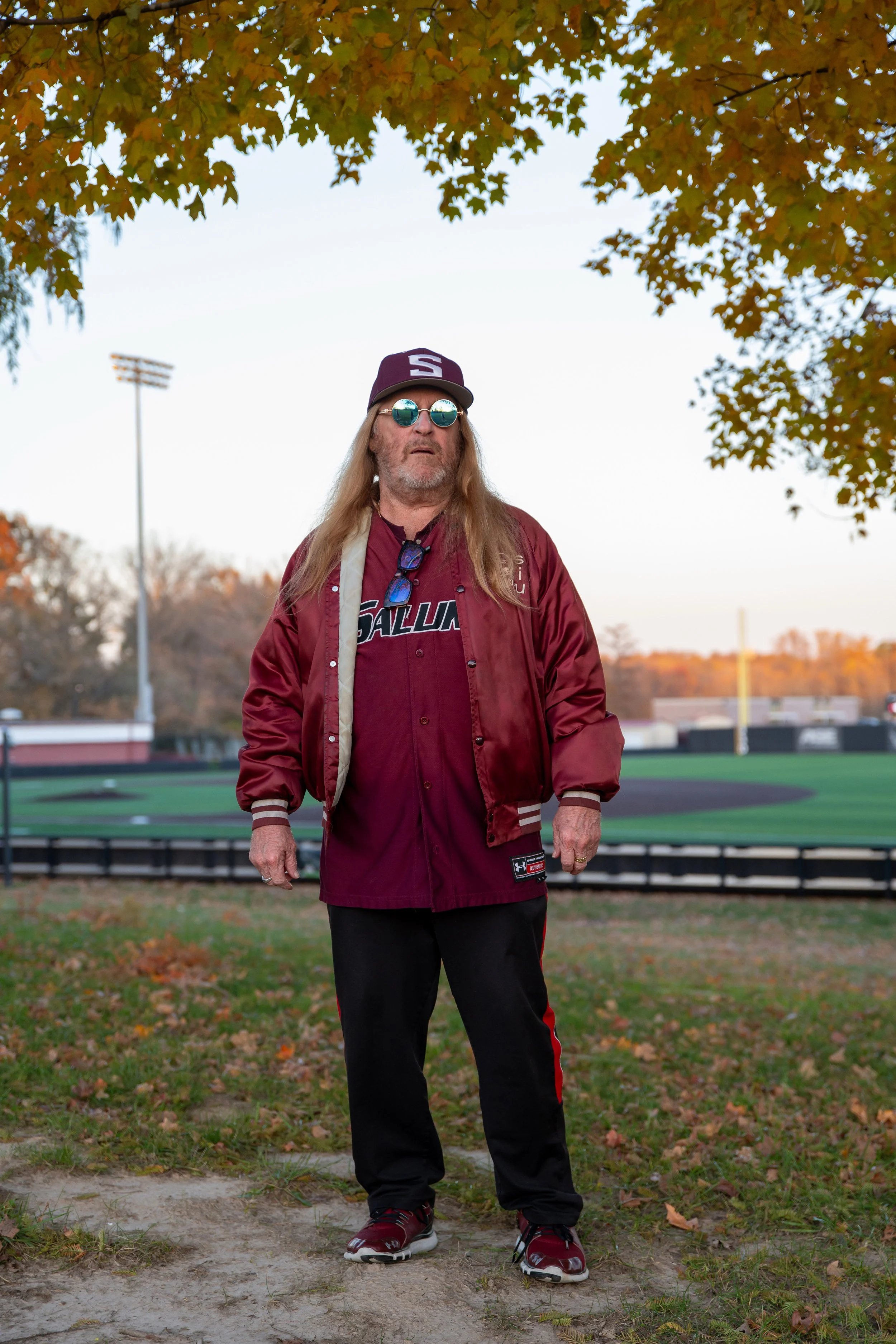 Dan “Red Dog” Abbott, 67, poses for a portrait Wednesday Nov 12, 2025 on The Hill at Itchy Jones Stadium in Carbondale Ill. Abbott has been a long time Saluki baseball fan for decades. He is part of the “Hill Gang,” who supports the team on and off t