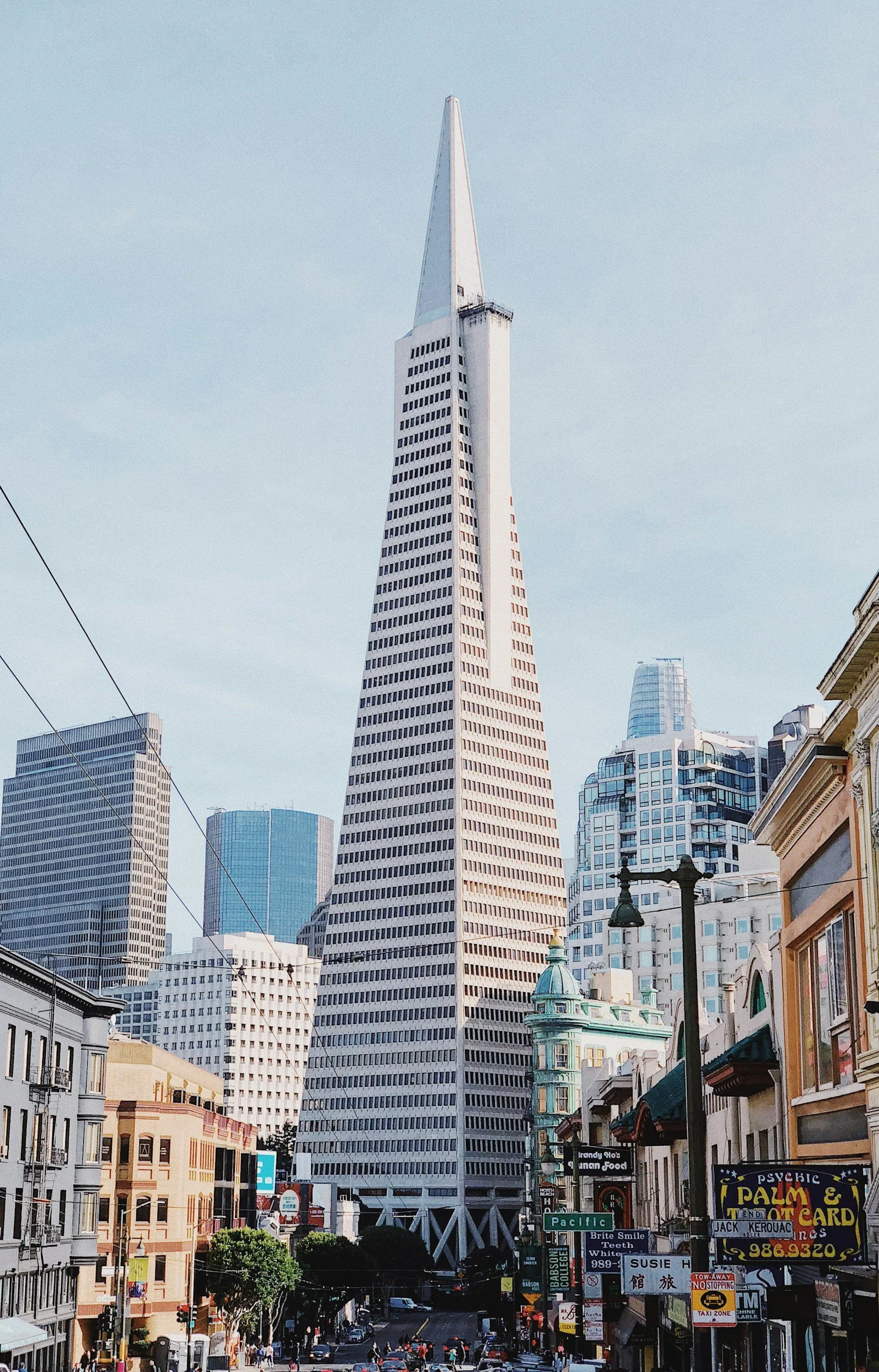 City street scene with the Transamerica Pyramid building in San Francisco skyline, surrounded by other high-rise buildings and street activity.