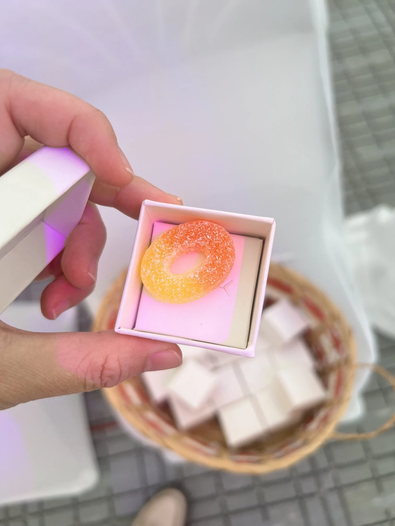 An open white box with a orange and yellow gummy ring inside.